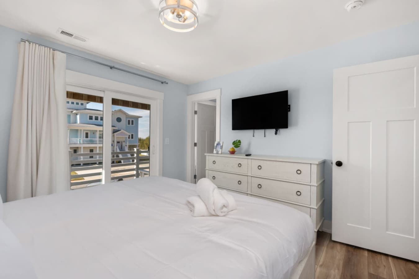 Cozy bedroom w/ balcony access, TV & dresser for relaxed downtime.