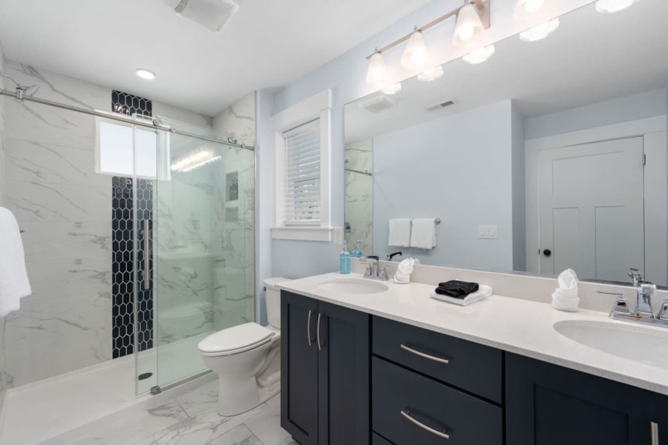 Fresh ensuite bath w/ glass shower, double vanity & crisp finishes.