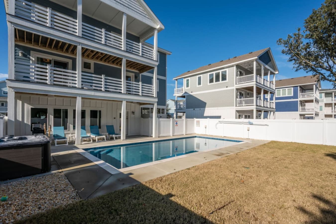 Rear of the home w/ stacked covered decks, private pool & hot tub on the deck below.
