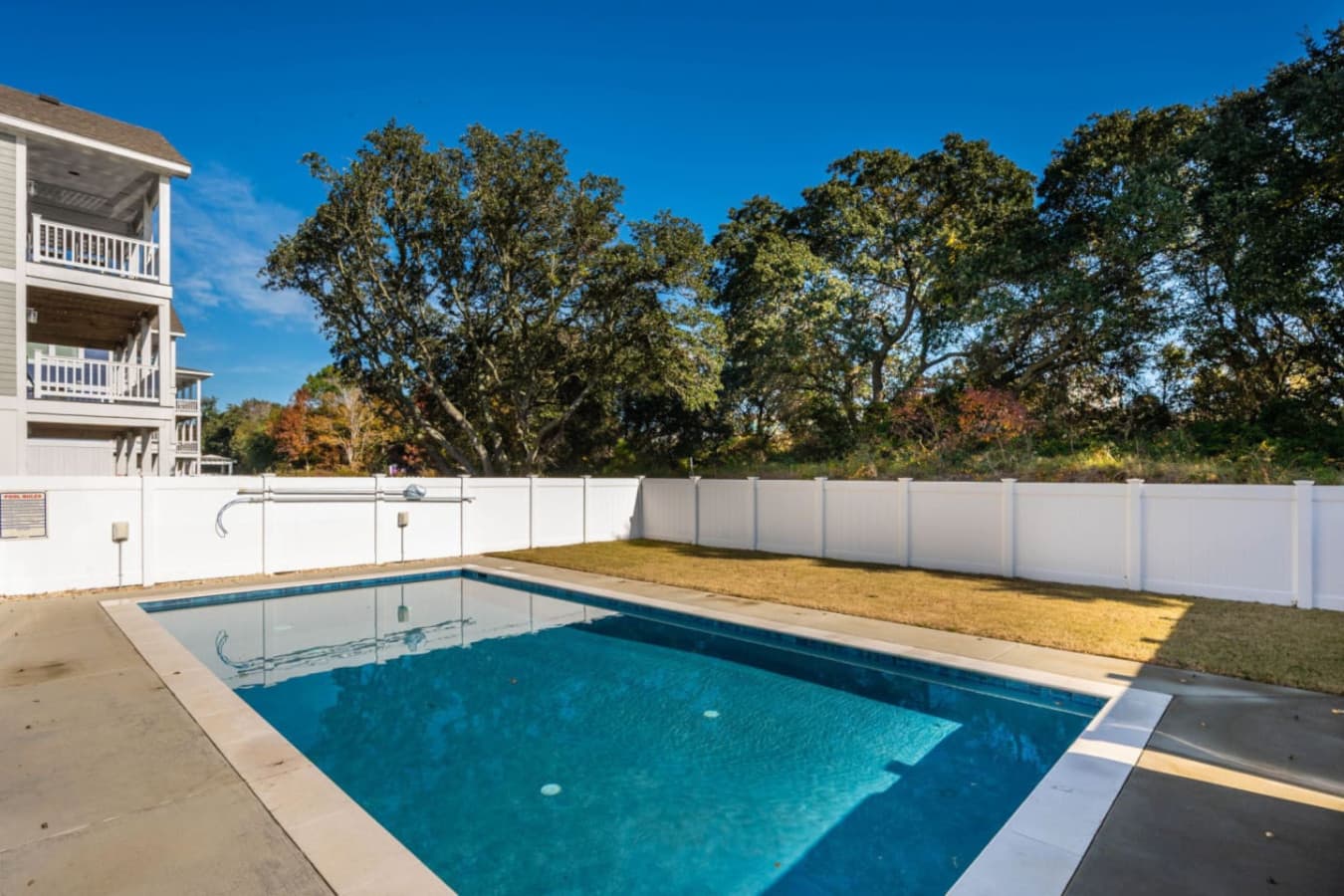 Private pool w/ wide concrete deck, white fencing & a treeline backdrop for afternoon swims.