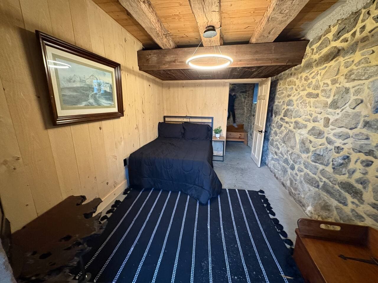 A cozy bedroom featuring a full-size bed, warm rustic barn-style décor, and a convenient in-room TV. Natural textures and farmhouse accents create a peaceful retreat perfect for unwinding after a long day.