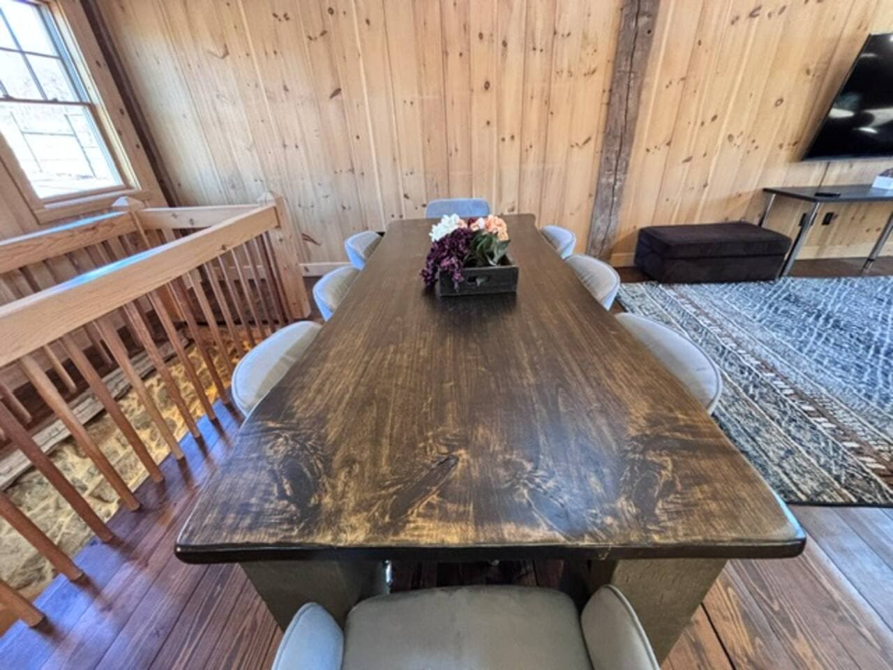 A bright and stylish dining room blending modern design with a cozy barn atmosphere. It features a solid wood farmhouse table, sleek modern chairs, and warm textures. Soft lighting and natural materials make the space feel comfortably rustic.