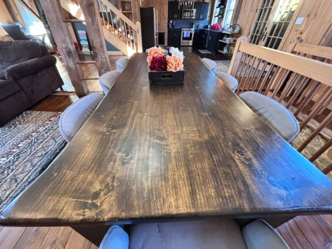 A bright and stylish dining room blending modern design with a cozy barn atmosphere. It features a solid wood farmhouse table, sleek modern chairs, and warm textures. Soft lighting and natural materials make the space feel comfortably rustic.
