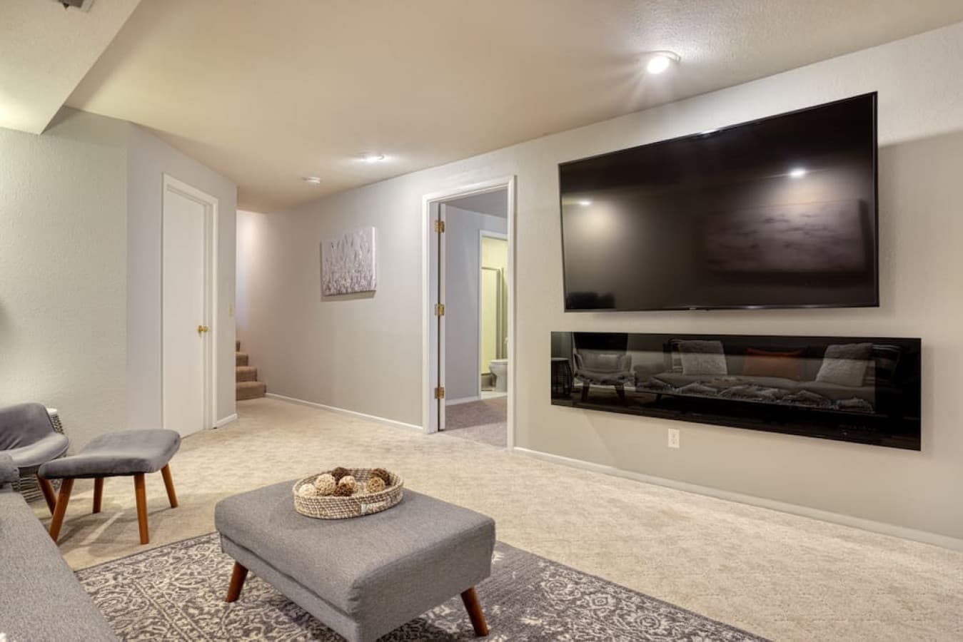Grand tv above fireplace in bottom level living room area. Final king bedroom in background