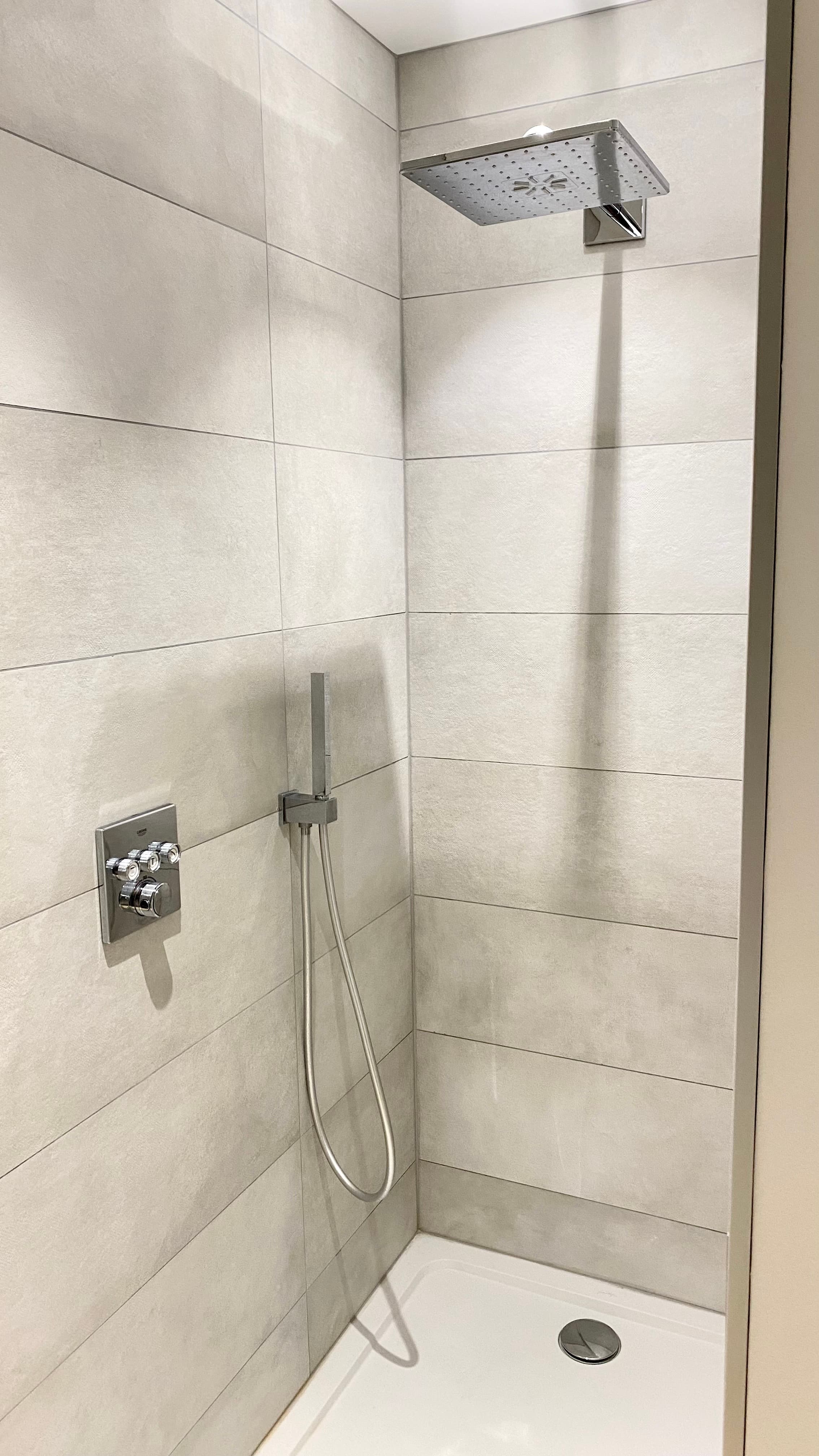 Douche spacieuse avec paroi en verre dans une salle de bain élégante aux finitions modernes.