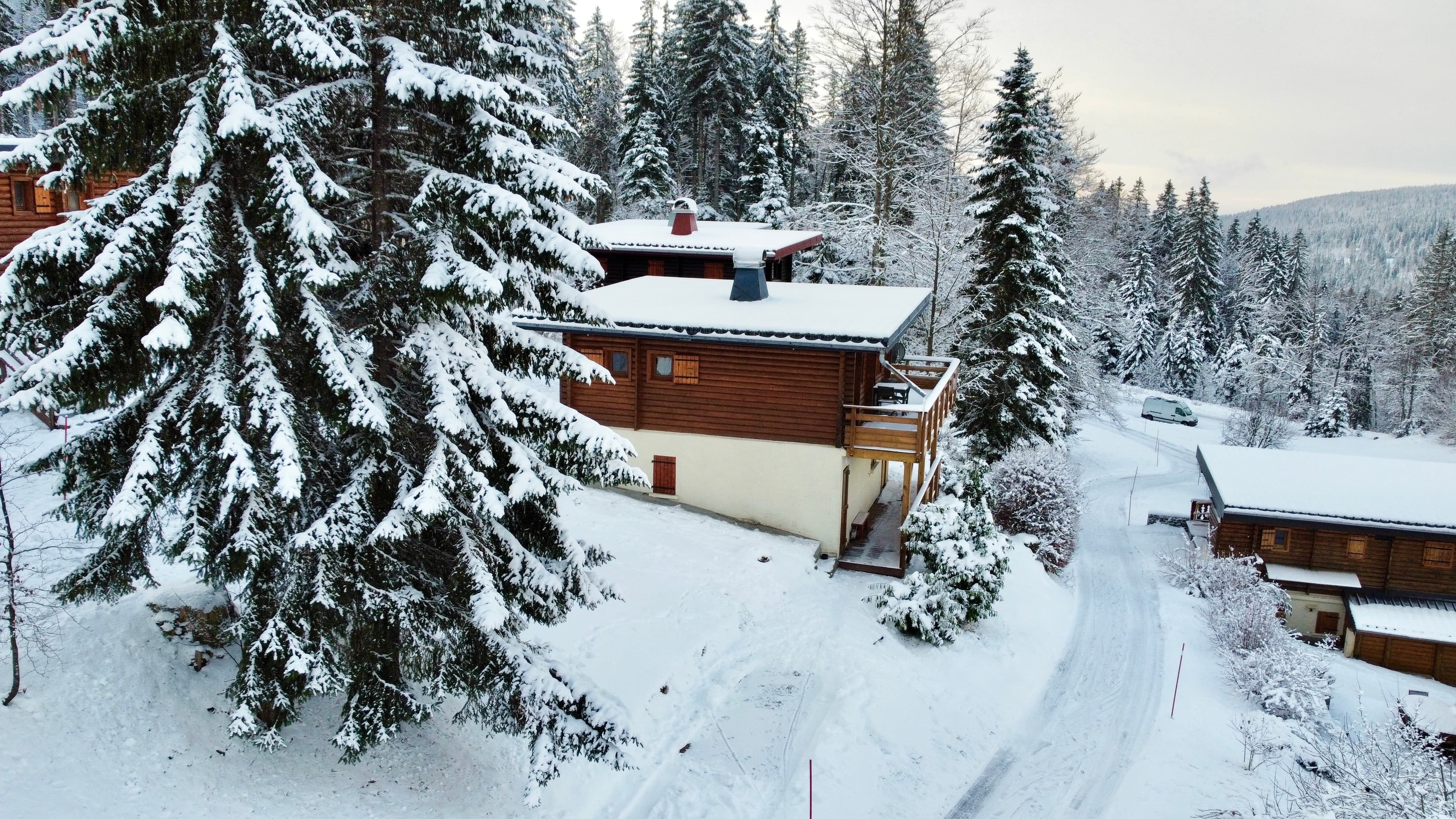 Vue aérienne d'un chalet aux Rousses, entouré de paysages enneigés sous un ciel d'hiver. 2