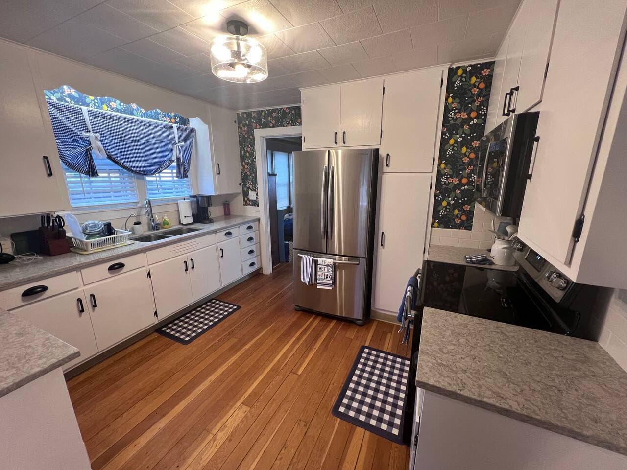 Corian countertops complete with electric range/oven, Ninja coffeemaker, over-the-range microwave, refrigerator, toaster, and bullet blender.