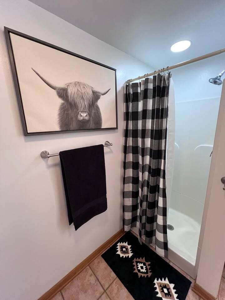 Shower stall has new shower head and curtains.