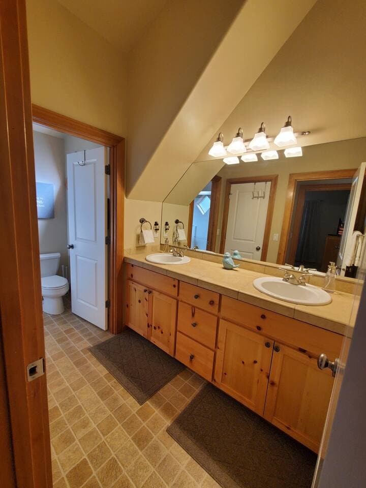 Upstairs bathroom with 2 sinks and private bath/shower combo and toilet room.