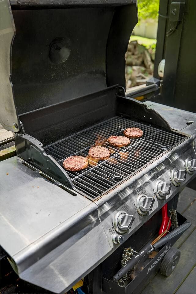 enjoy this large barbecue grill with side burner, extra propane tanks are on the side of the house near the entrance