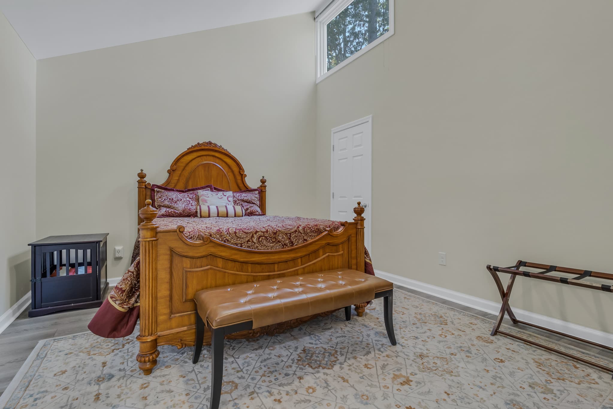 Queen bed room with crate for small or medium-sized dog.