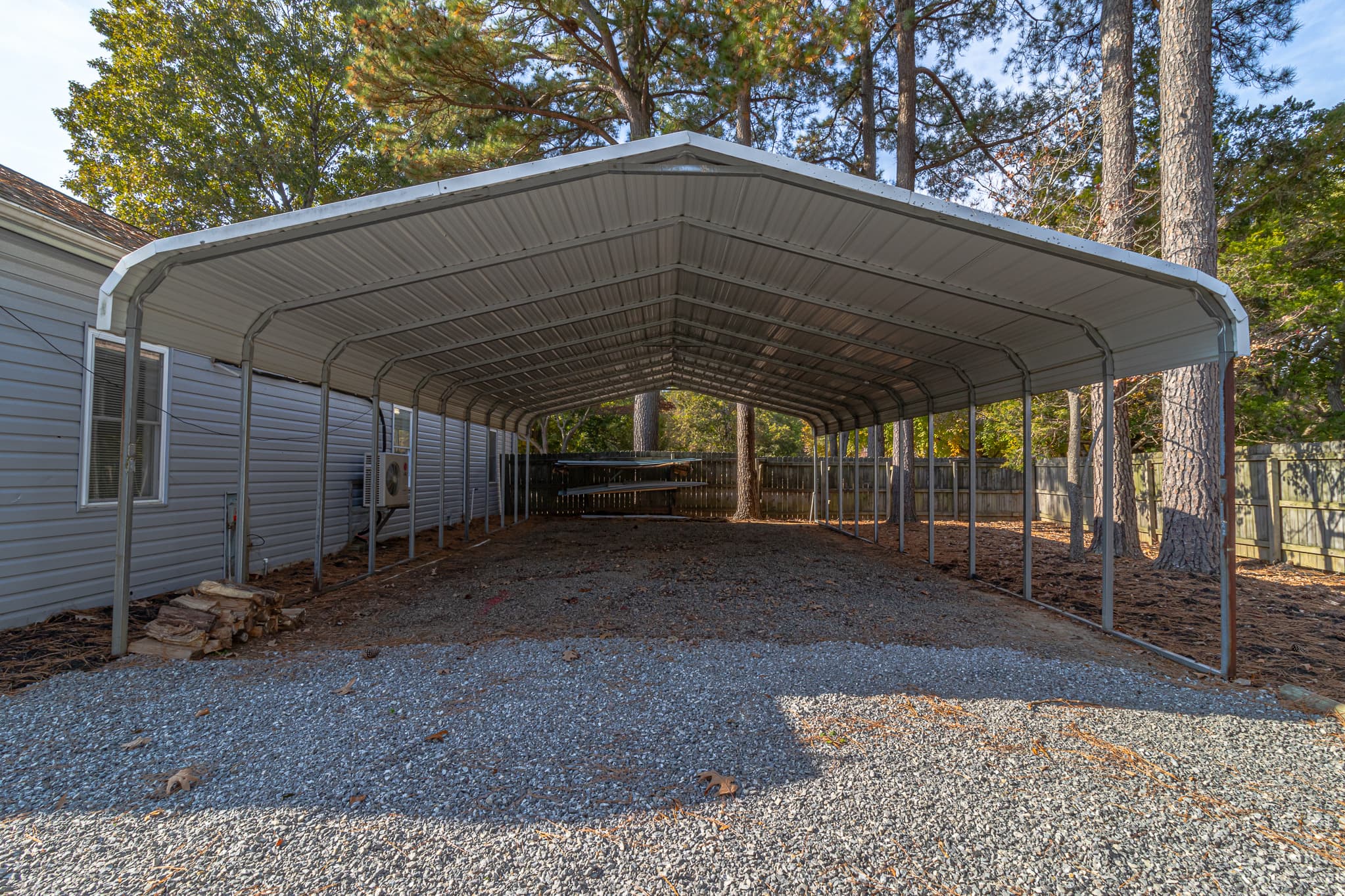 24 ft. wide carport behind garage. It's 8 ft. high (lowest point) and 10.5 ft. high (highest point).