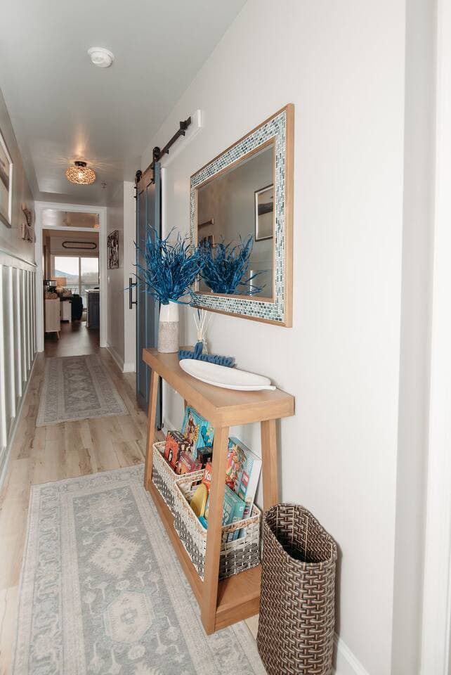 Step into a warm and stylish entryway that blends comfort and charm. This thoughtfully decorated hallway features a large mirror, cozy lighting, and a curated selection games to make you feel right at home from the moment you arrive.

