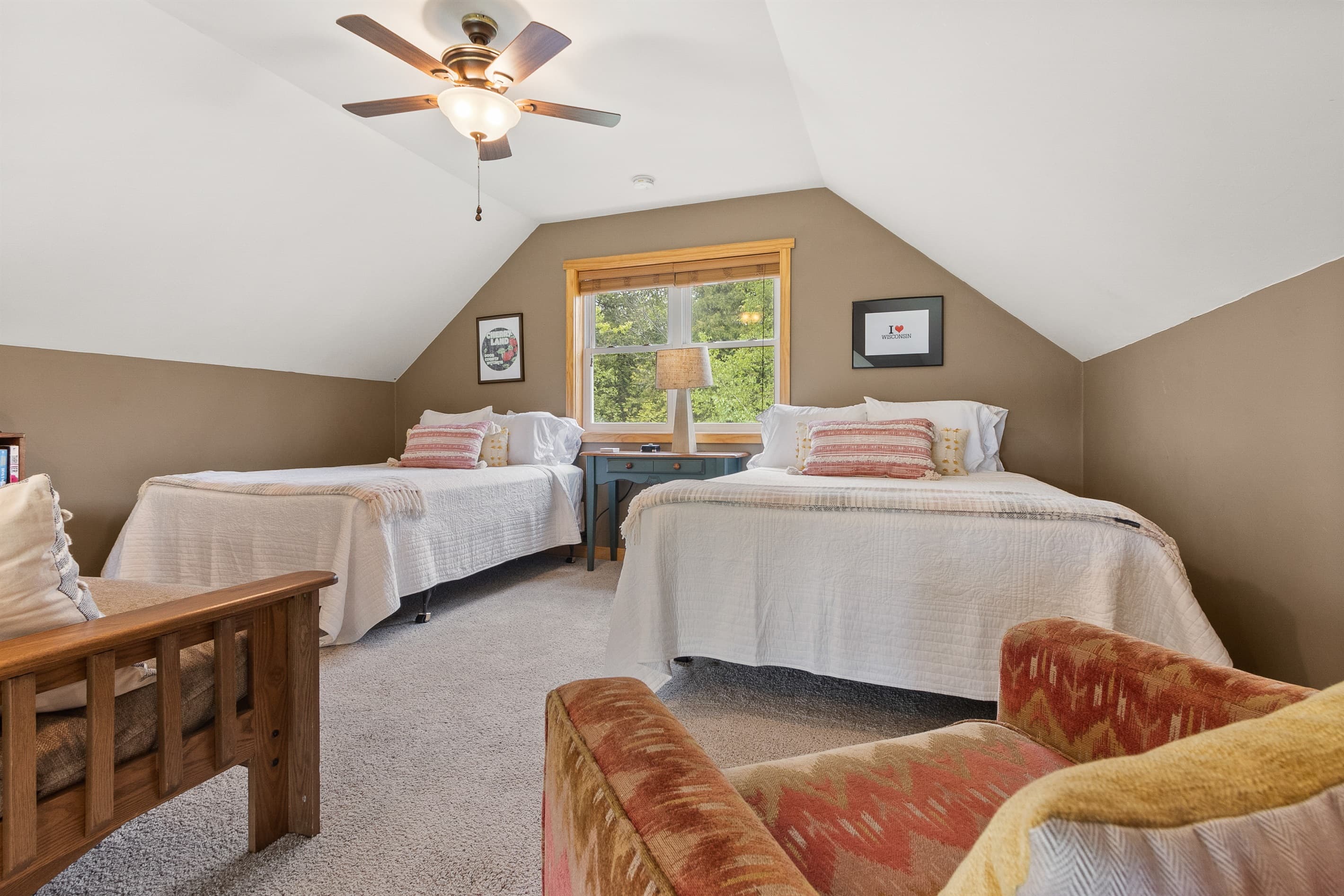 Two beds tucked under the roofline with a window between them. The loft at Sawyer Harbor Retreat is a properly comfortable upper floor, not an afterthought.