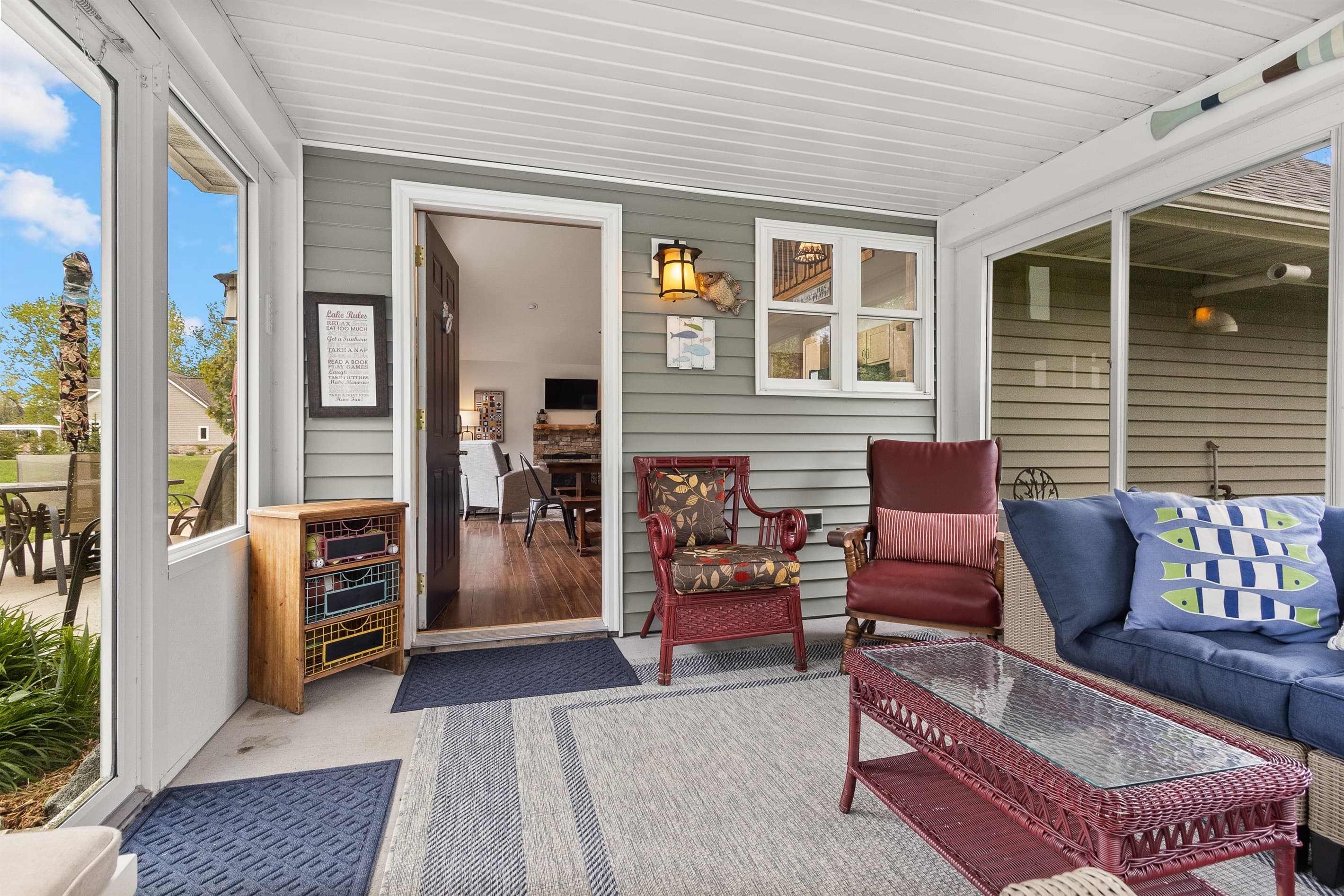 Step into the screened porch and the stone fireplace is already glowing through the door. Bluetooth speaker on the shelf, seating for the group, and the yard right outside. The in-between place everyone ends up.
