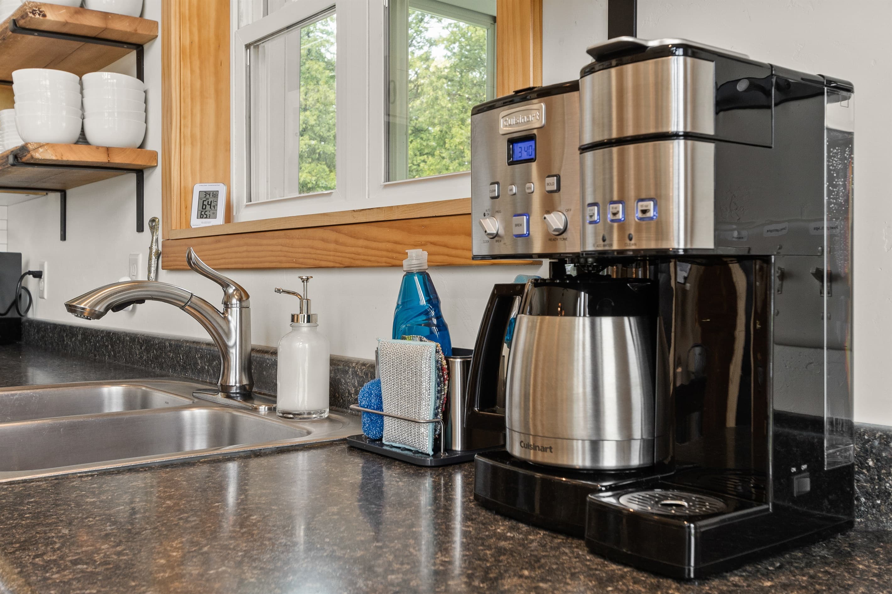 A dedicated coffee setup with a Cuisinart brewer and shelves of mugs — because the best Door County mornings start before you've said a word to anyone. This is where that happens.