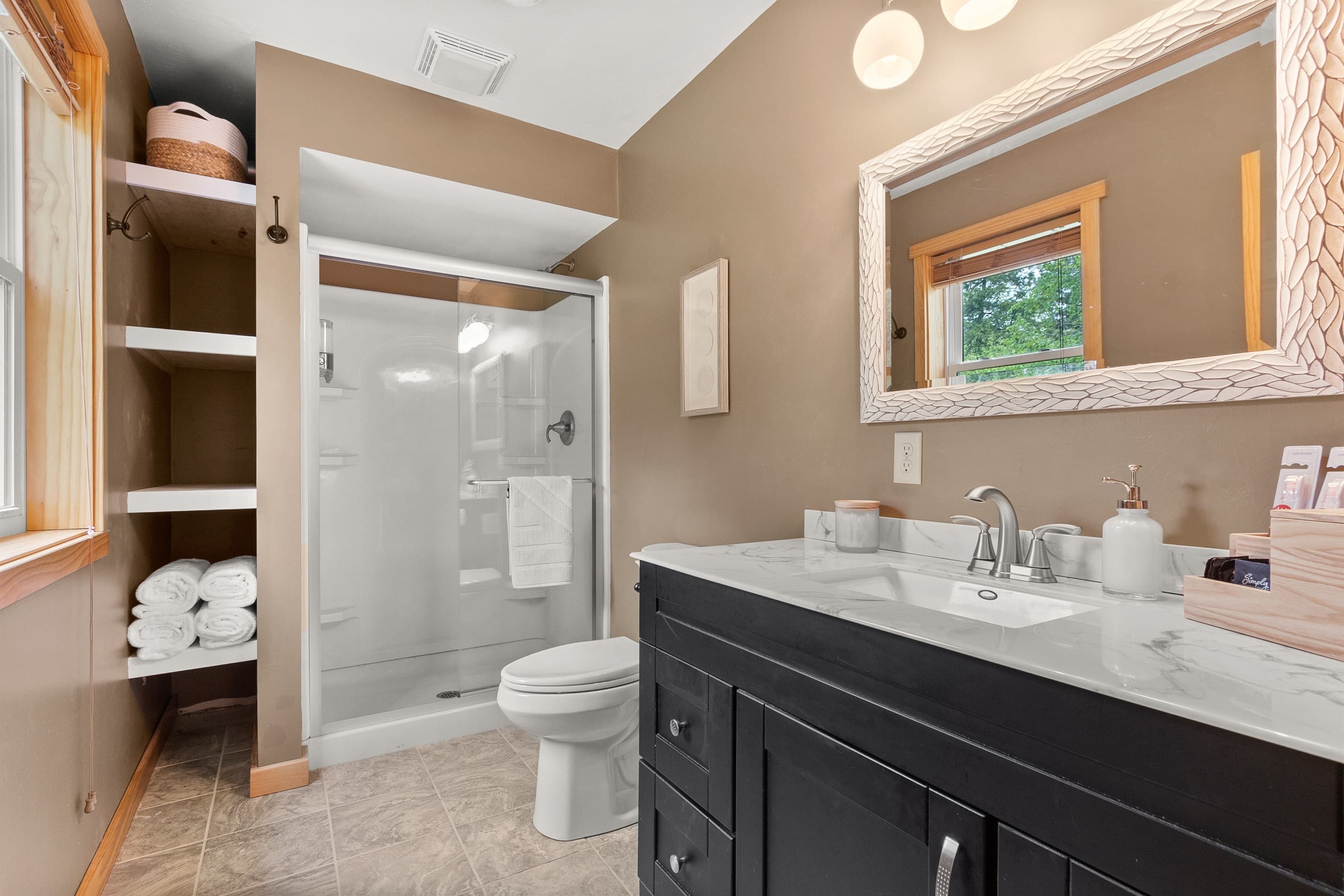 Rinse off after a day on Sawyer Harbor — the walk-in shower is stocked with shampoo, conditioner, and body wash, and fresh towels are stacked right outside on the built-in shelf.
