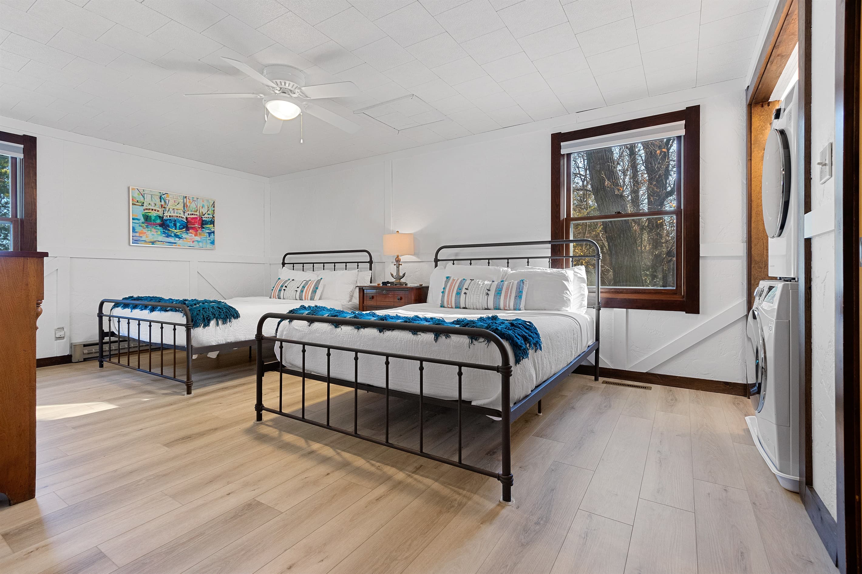 Two queen beds, crisp white bedding, and blue throws that look like they were made for a Door County cottage. The laundry is right there too — because a week-long trip should actually feel like a week.