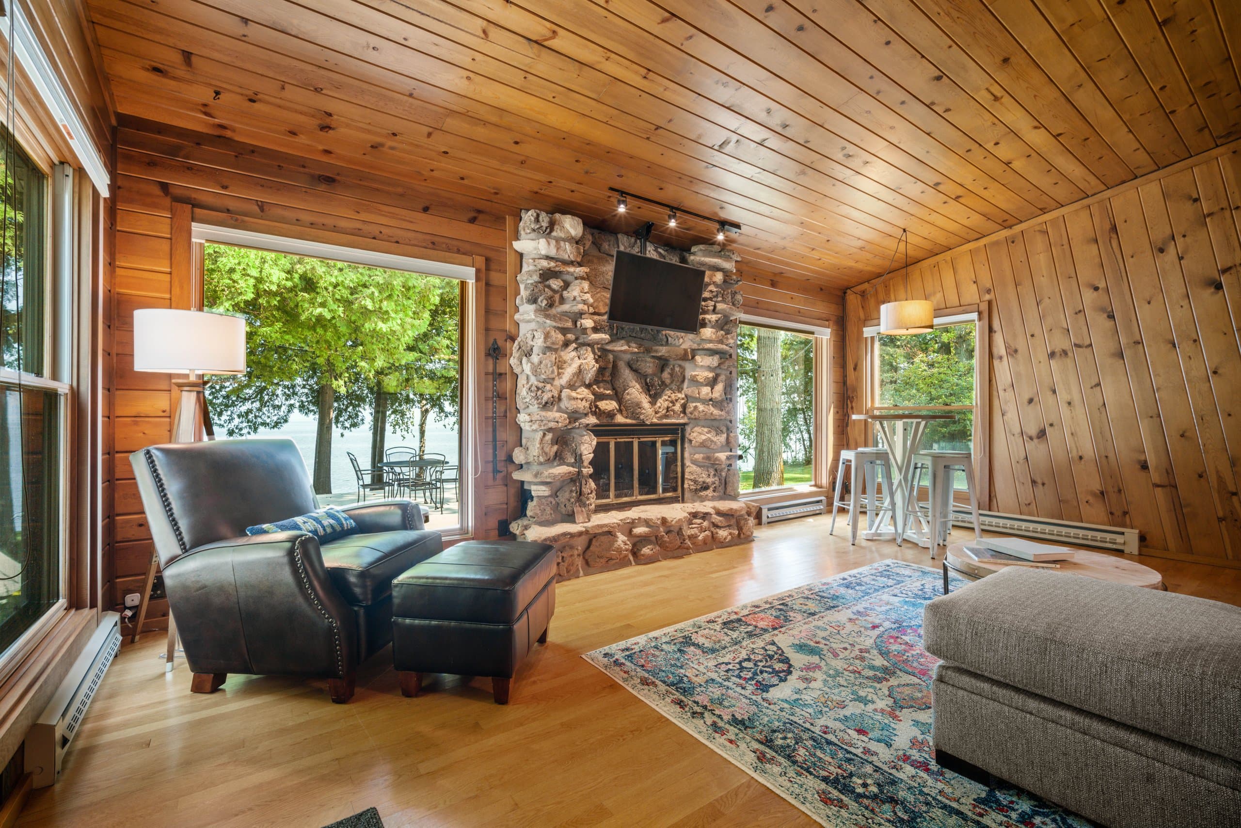 Floor-to-ceiling stone, a fire burning, the bay framed on both sides, and a leather chair pulled right up to it. This fireplace is why people come back every fall.