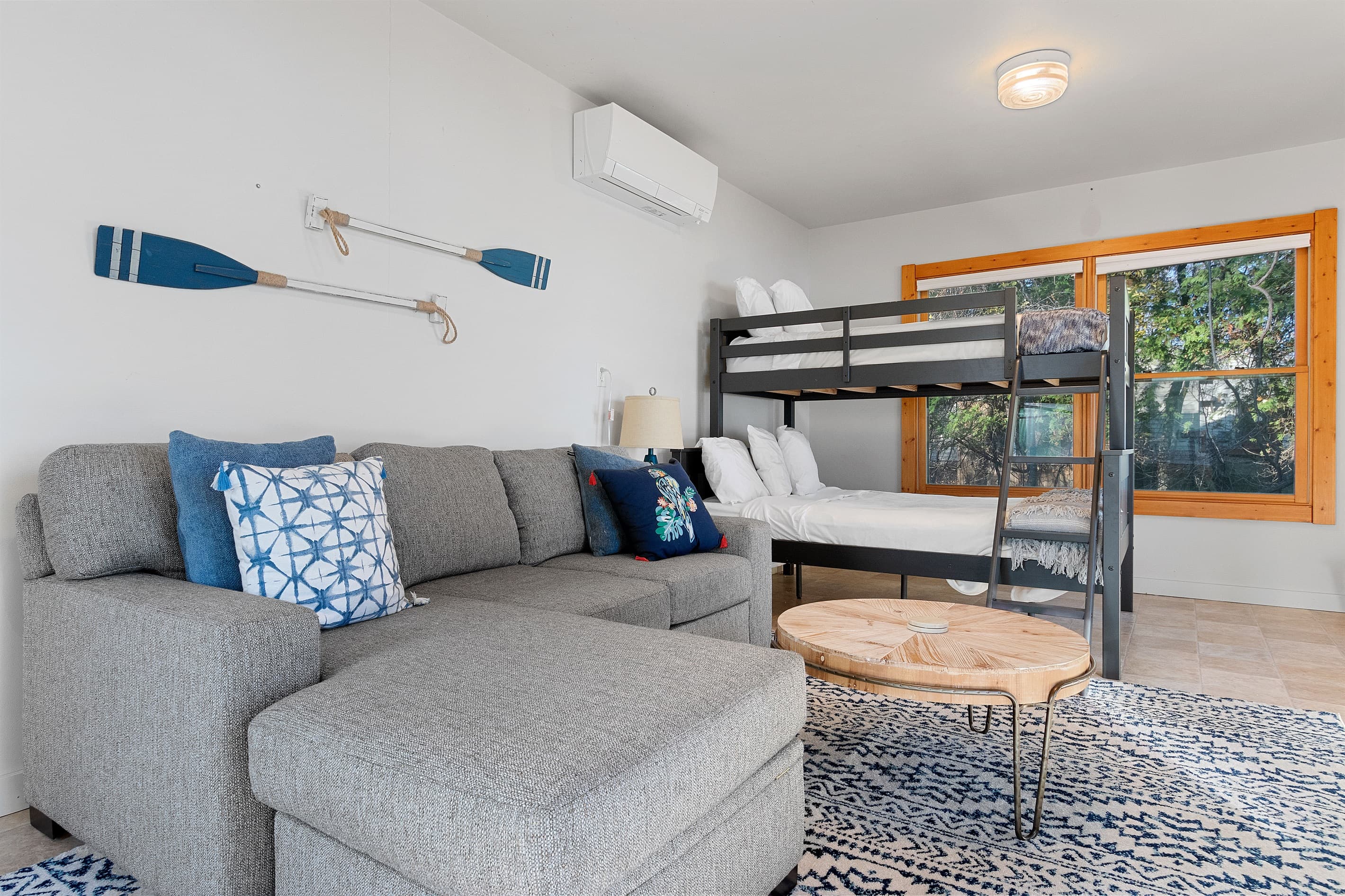 It's not just a room — the bunkhouse is its own little world. Sofa, TV, bunk beds, and enough windows to never feel cut off from the bay outside. Kids will never want to leave.