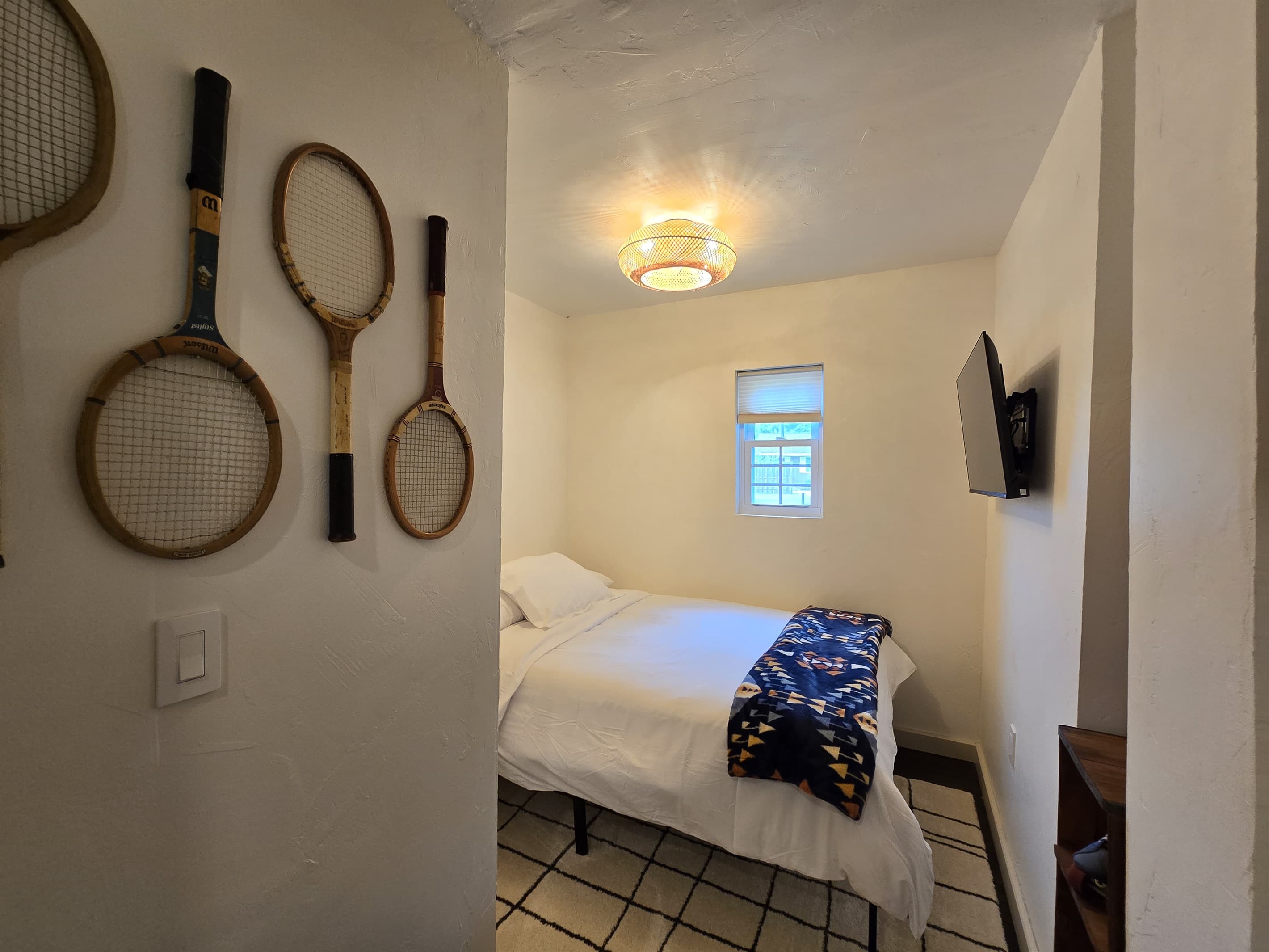 - Charming bedroom with playful vintage racket decor   - Soft bedding and warm ambient light for cozy rest   - A unique space that adds personality to your stay