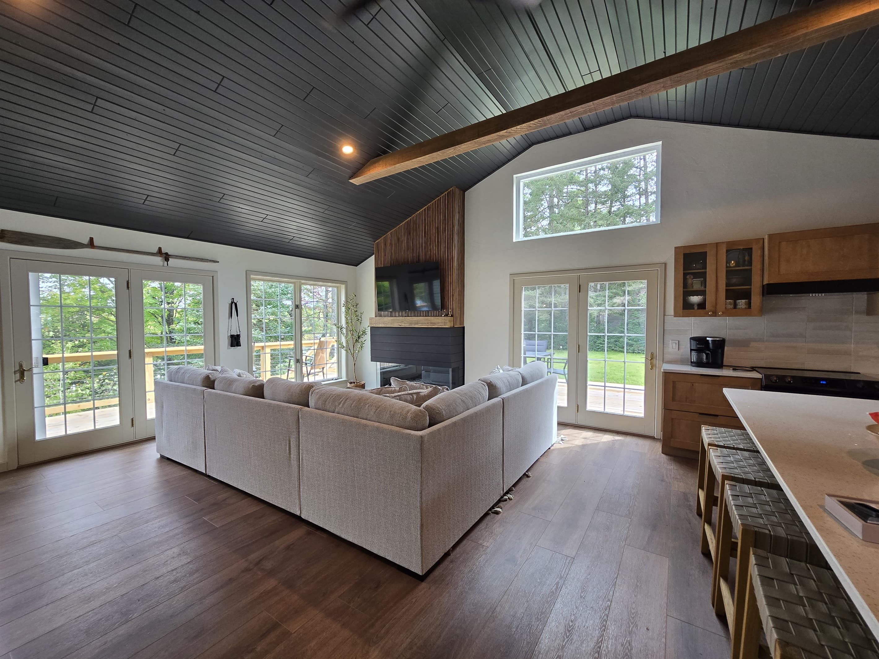 Gather in this inviting living area with a stunning fireplace! Large windows, a plush sectional, and a modern kitchenette create a warm space for unforgettable memories. 