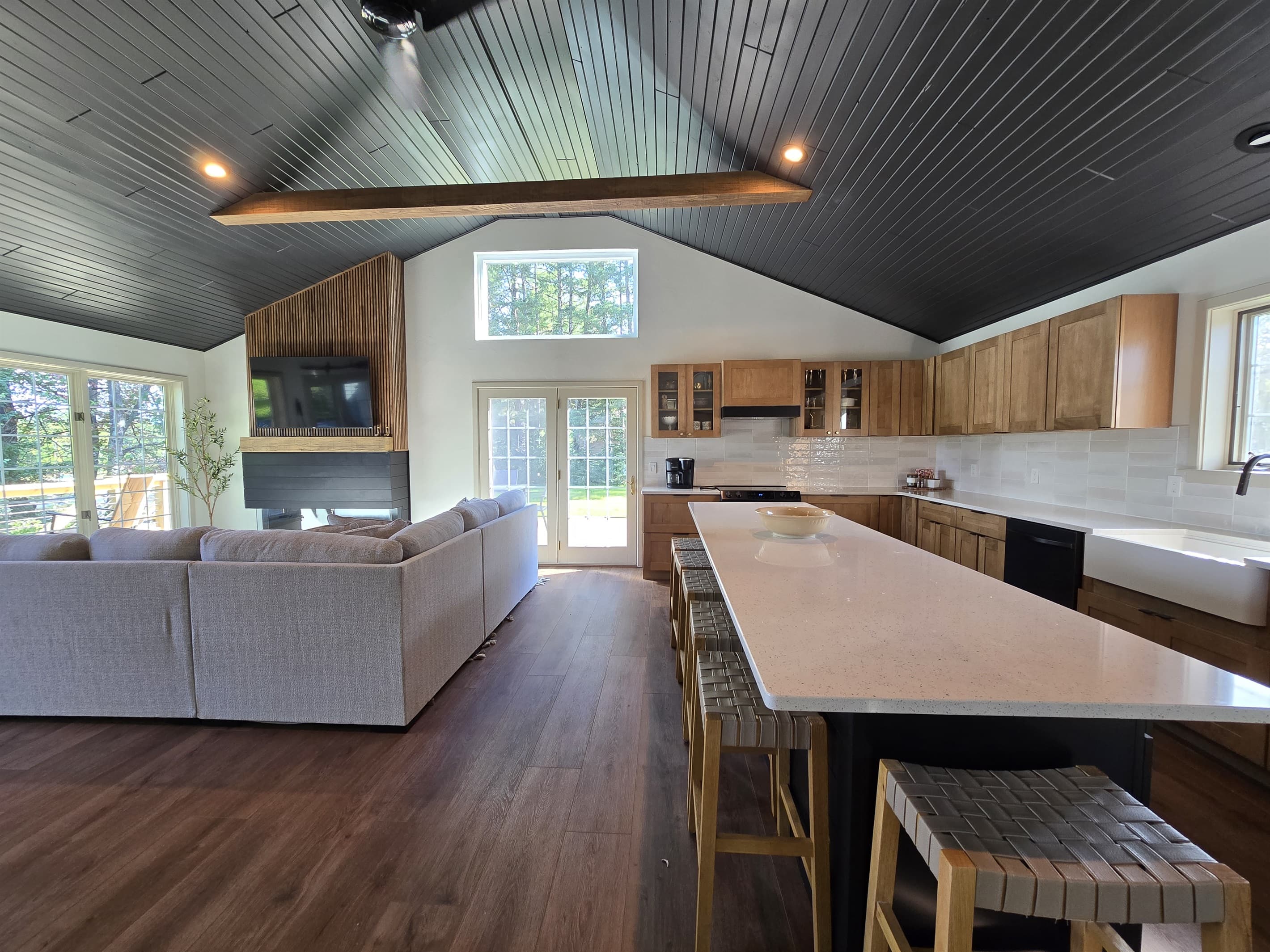 Bright and airy lake house kitchen with open floor plan. Modern island with seating, high-end appliances, and lots of natural light. Connects seamlessly to the living area with comfortable seating, creating a perfect space for entertaining or unwinding.