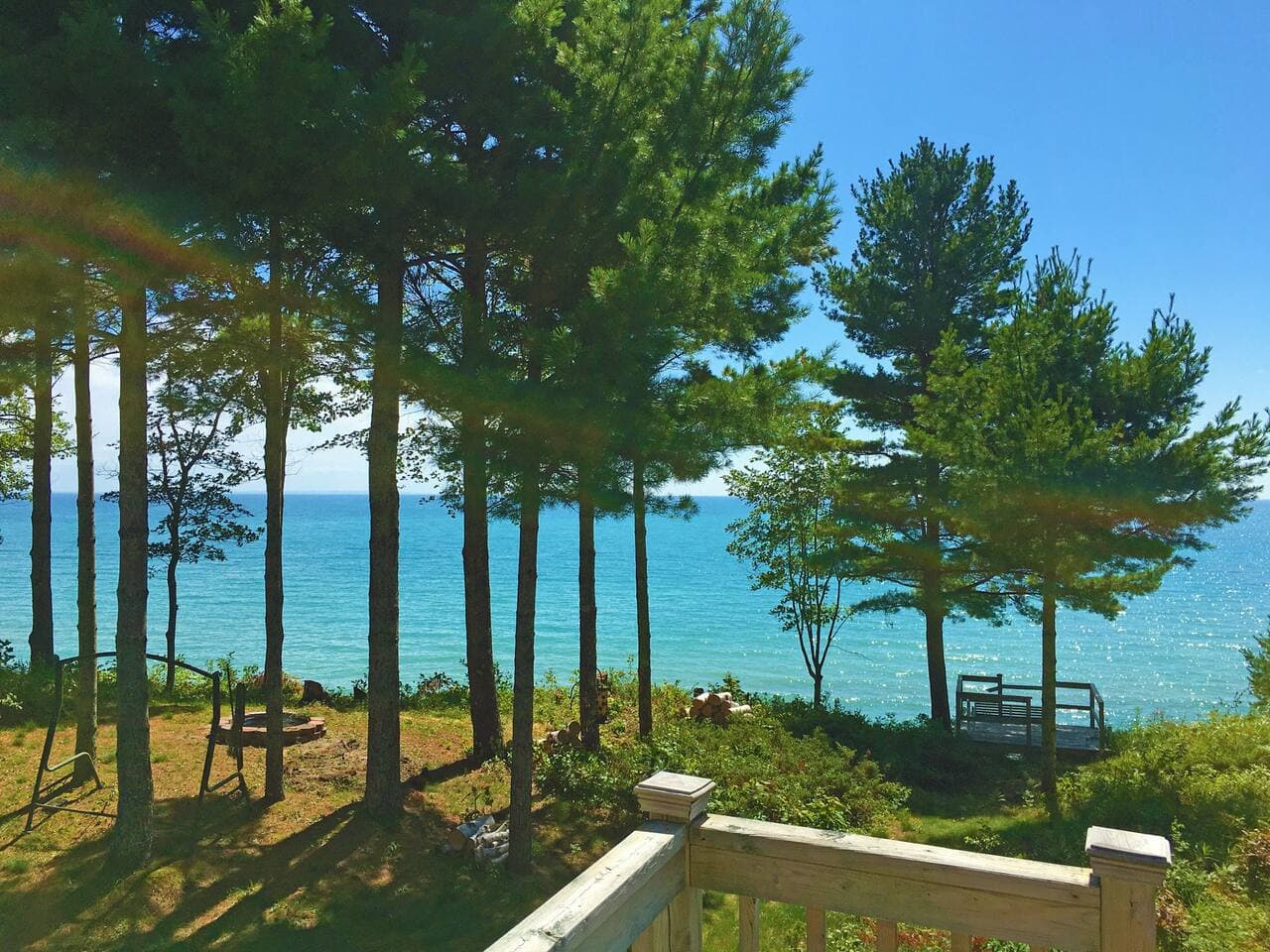View of wide open Lake Michigan's blue waters from primary suite deck toward the stairs leading down to the beach