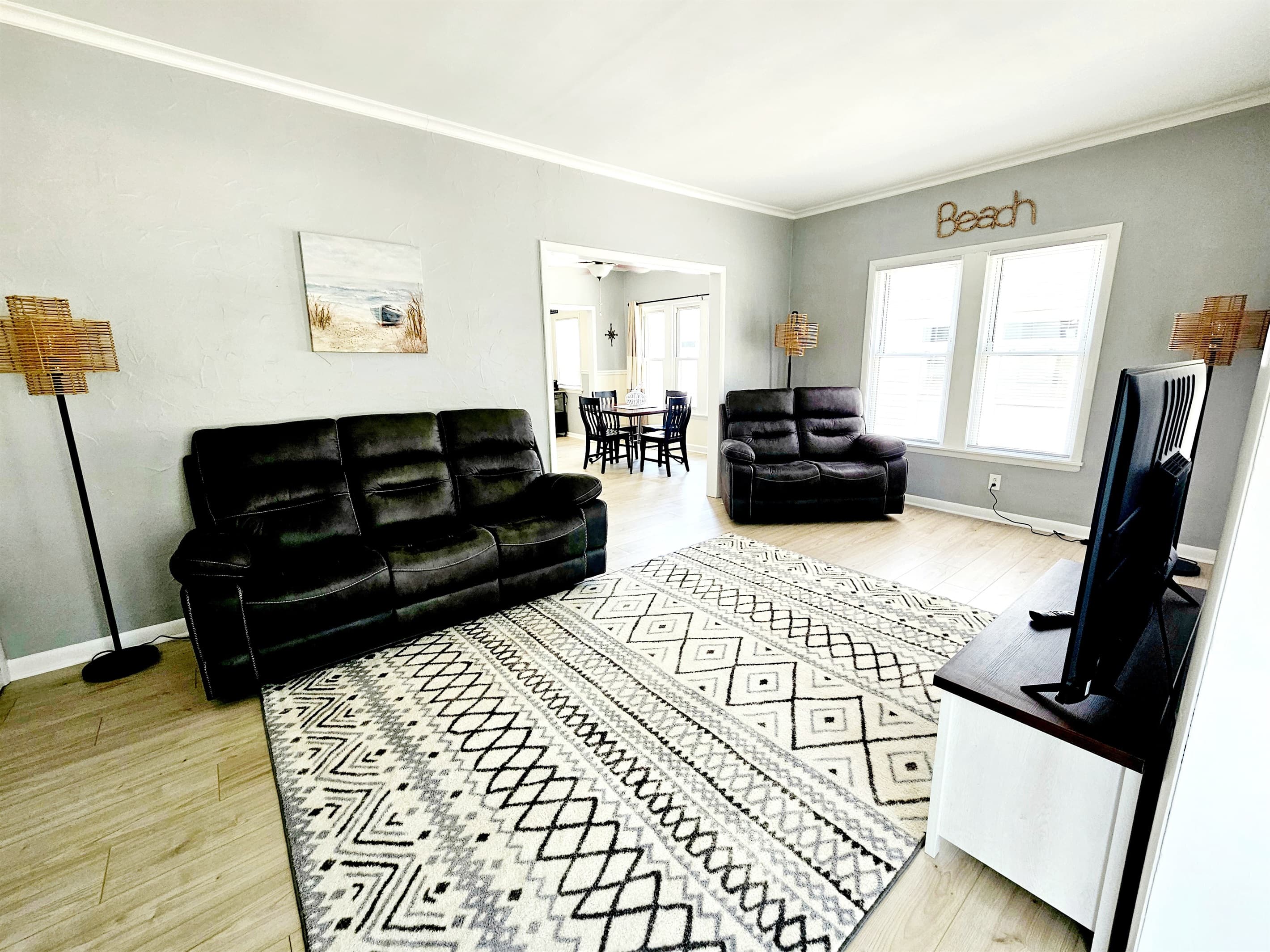 Living room includes 2 reclining sofas and a large smart TV with tons of natural light and views of the lake