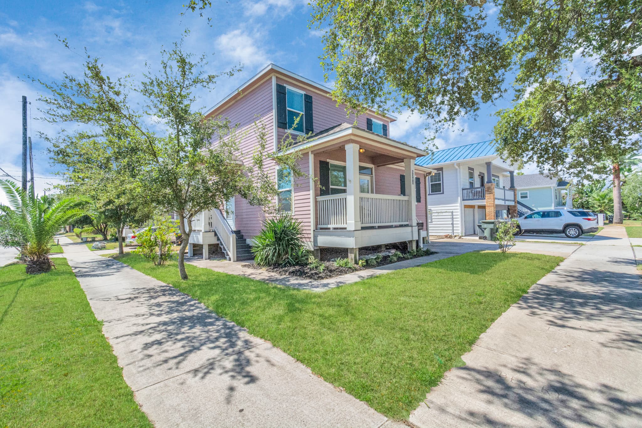Summer Bliss on its corner lot in Galveston — a charming home with a large front yard, covered porch, and the beach just a short walk away.