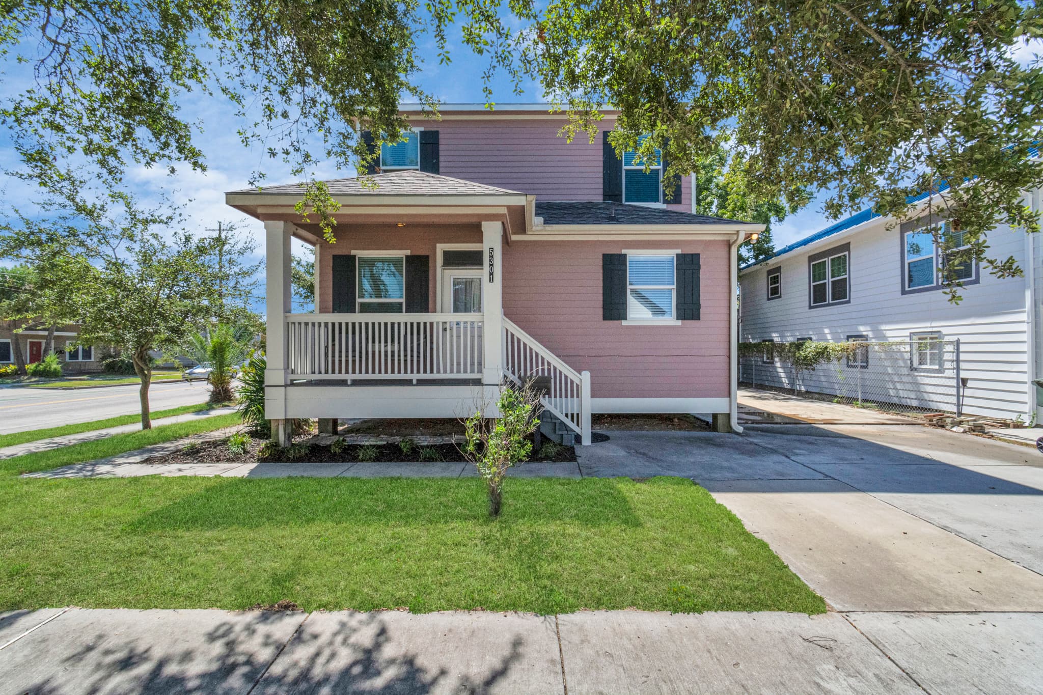 The front entrance at Summer Bliss — a covered porch, lush green lawn, and a corner location that makes arrival easy from either street.