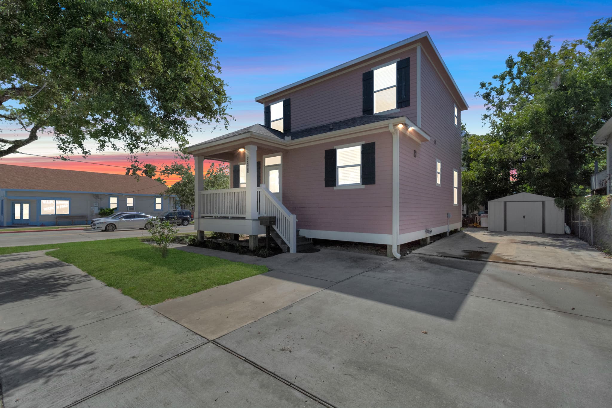 Summer Bliss from the street — a charming corner home in Galveston with a welcoming facade, lush landscaping, and the beach just blocks away.
