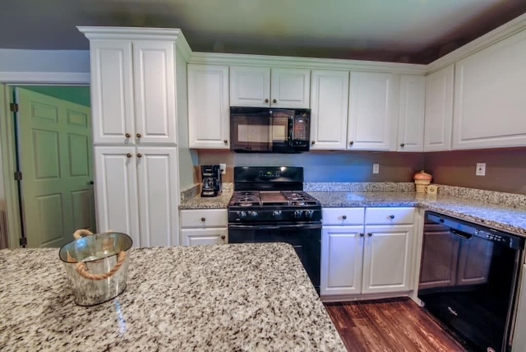 Stainless microwave hood, range, dishwasher, and full cabinetry — the kitchen is stocked and ready.