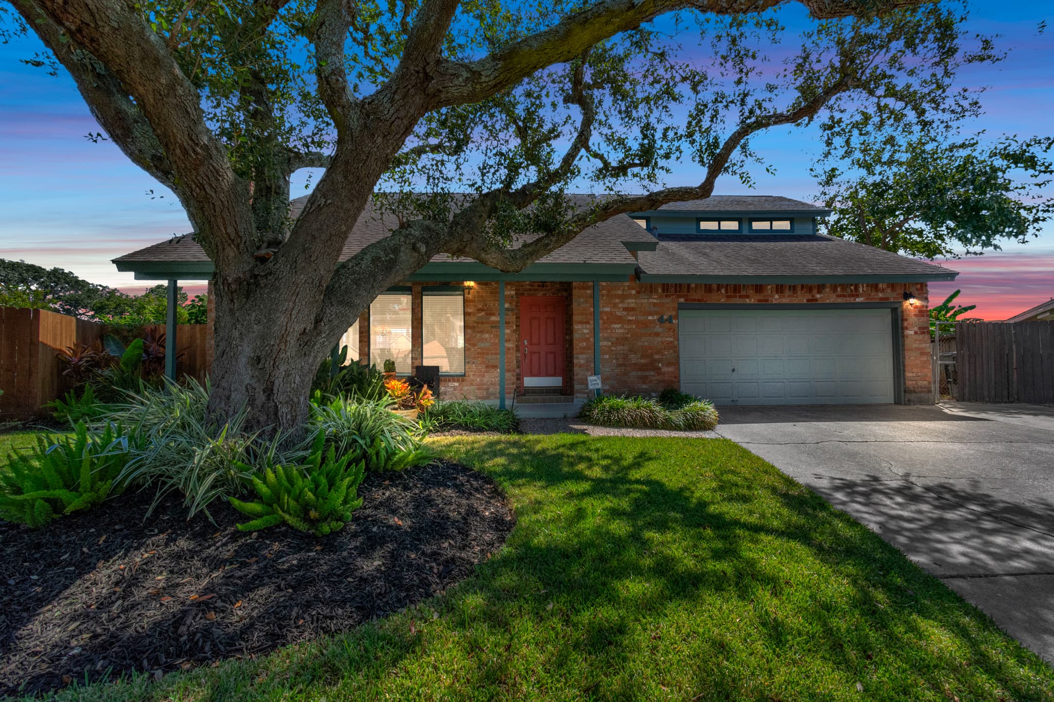 Lakeview Landing welcomes you home — beautifully lit exterior at night, framed by a magnificent heritage oak in Galveston TX.