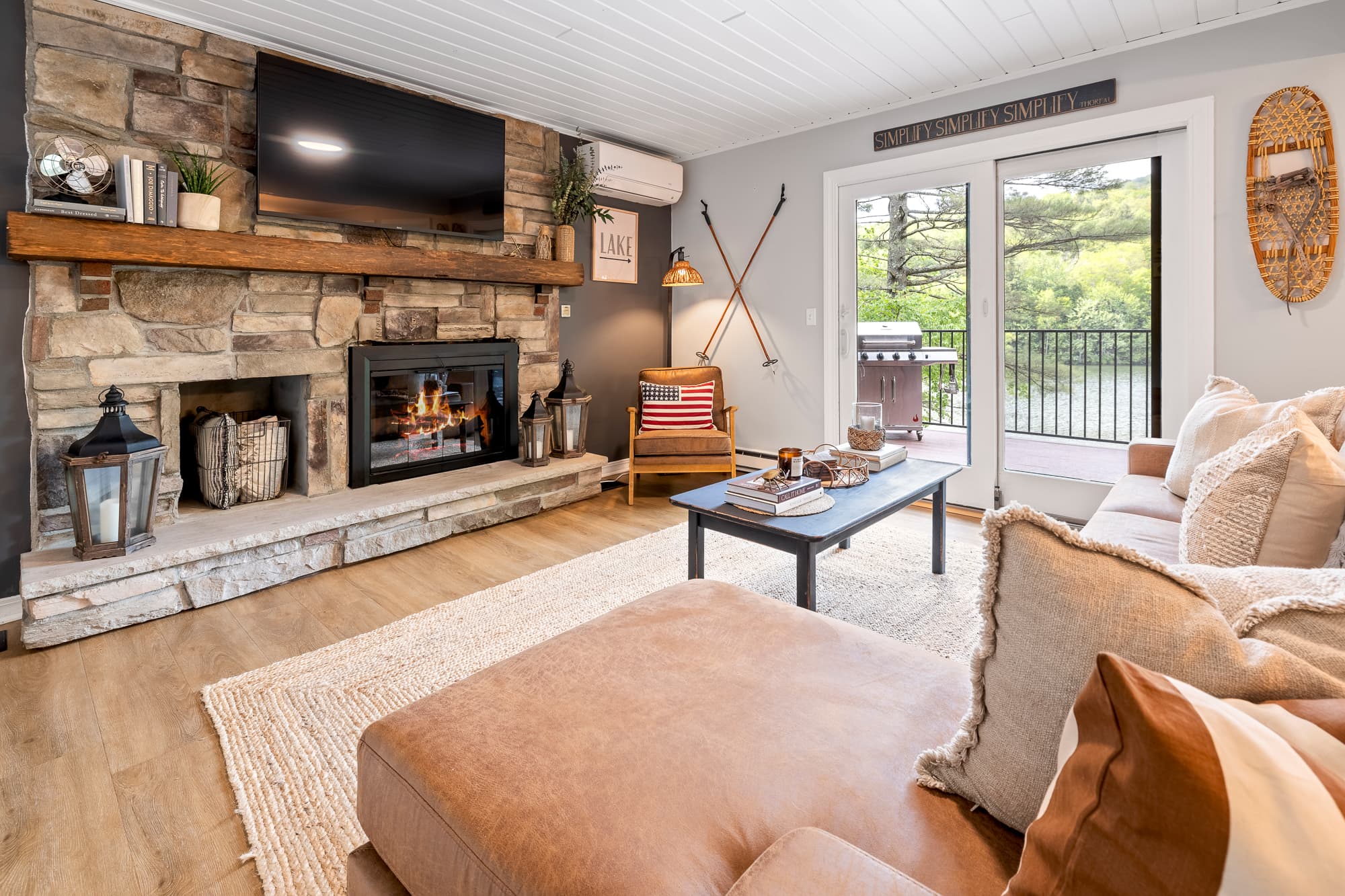 Cozy living room framed by stone fireplace & peaceful lake views