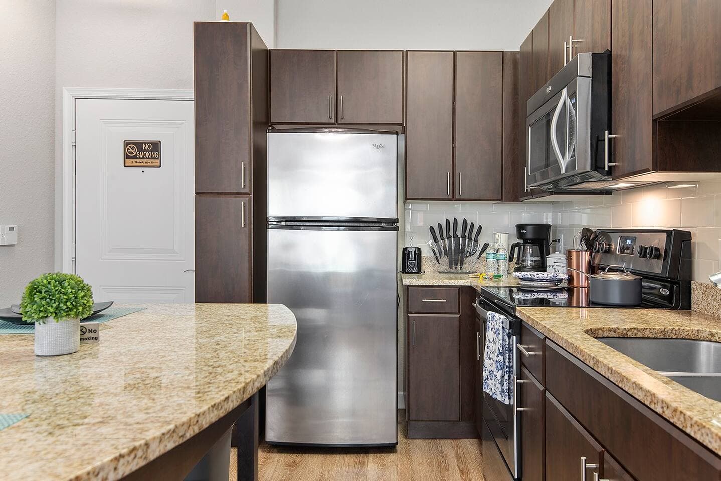 Full size fridge with ice maker, microwave, coffee maker, range, and oven - all for your at-home drink and meal needs.