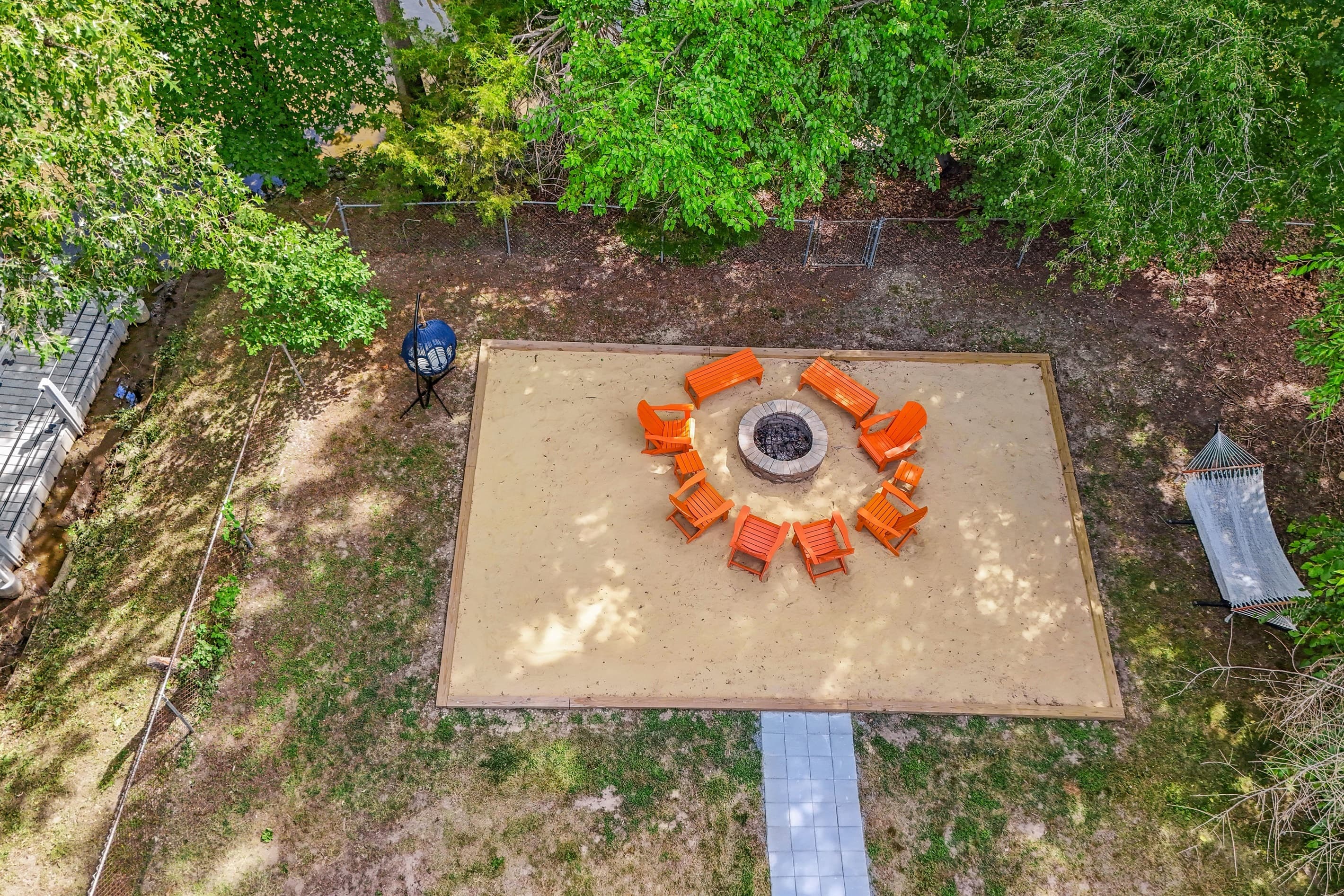 Several seating options available at the fire pit area - Adirondack chairs and benches, Egg chair, and hammock