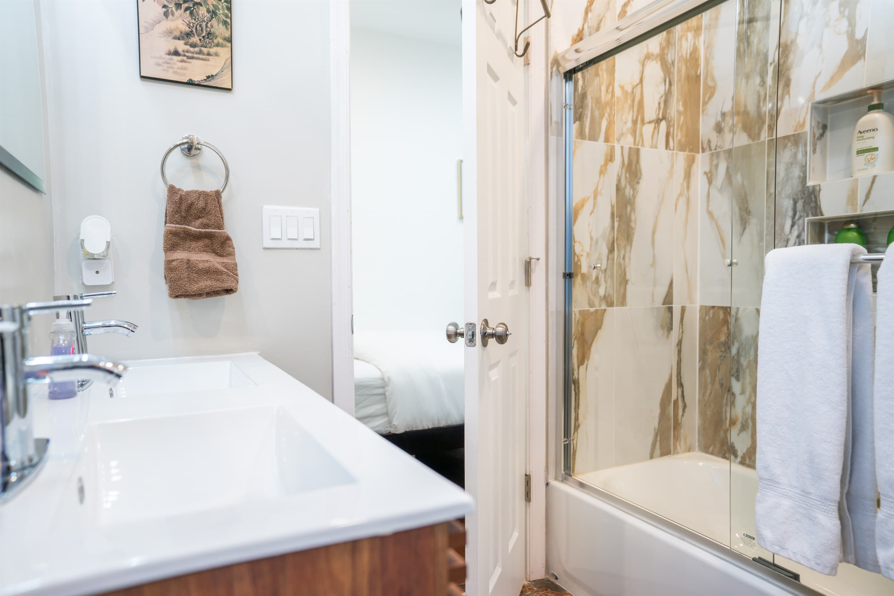 The jack and jill bathroom has a tub with sliding glass doors and a double vanity