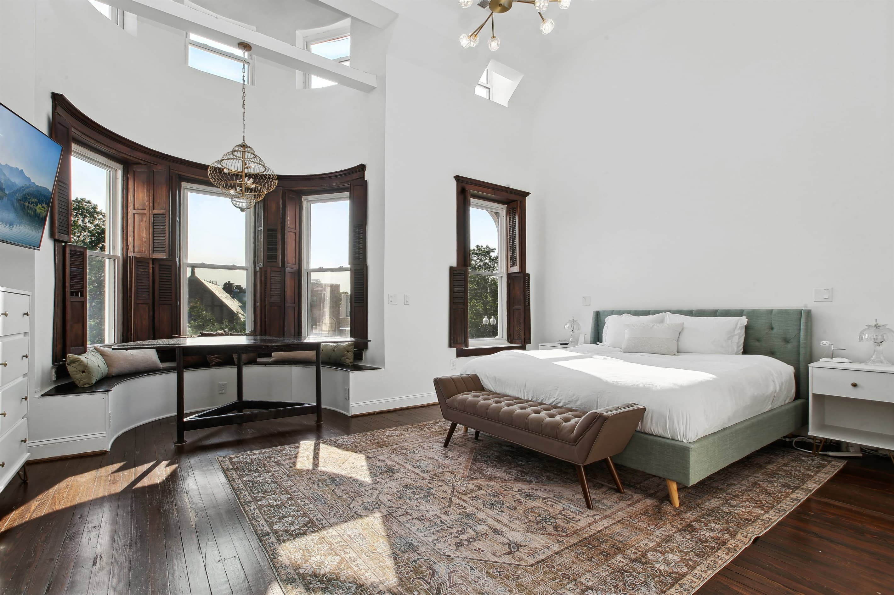 The primary bedroom has vaulted ceilings, a king bed, and a bench seating area