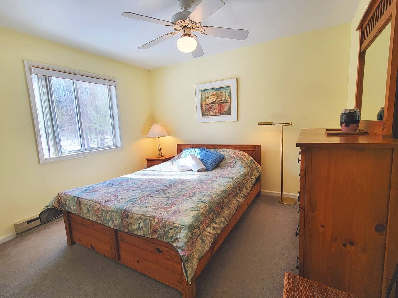 This bedroom has a queen size bed and a dresser with mirror