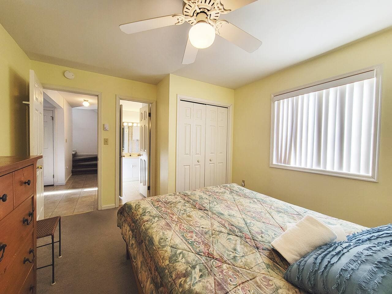 This bedroom has a queen size bed and a dresser with mirror