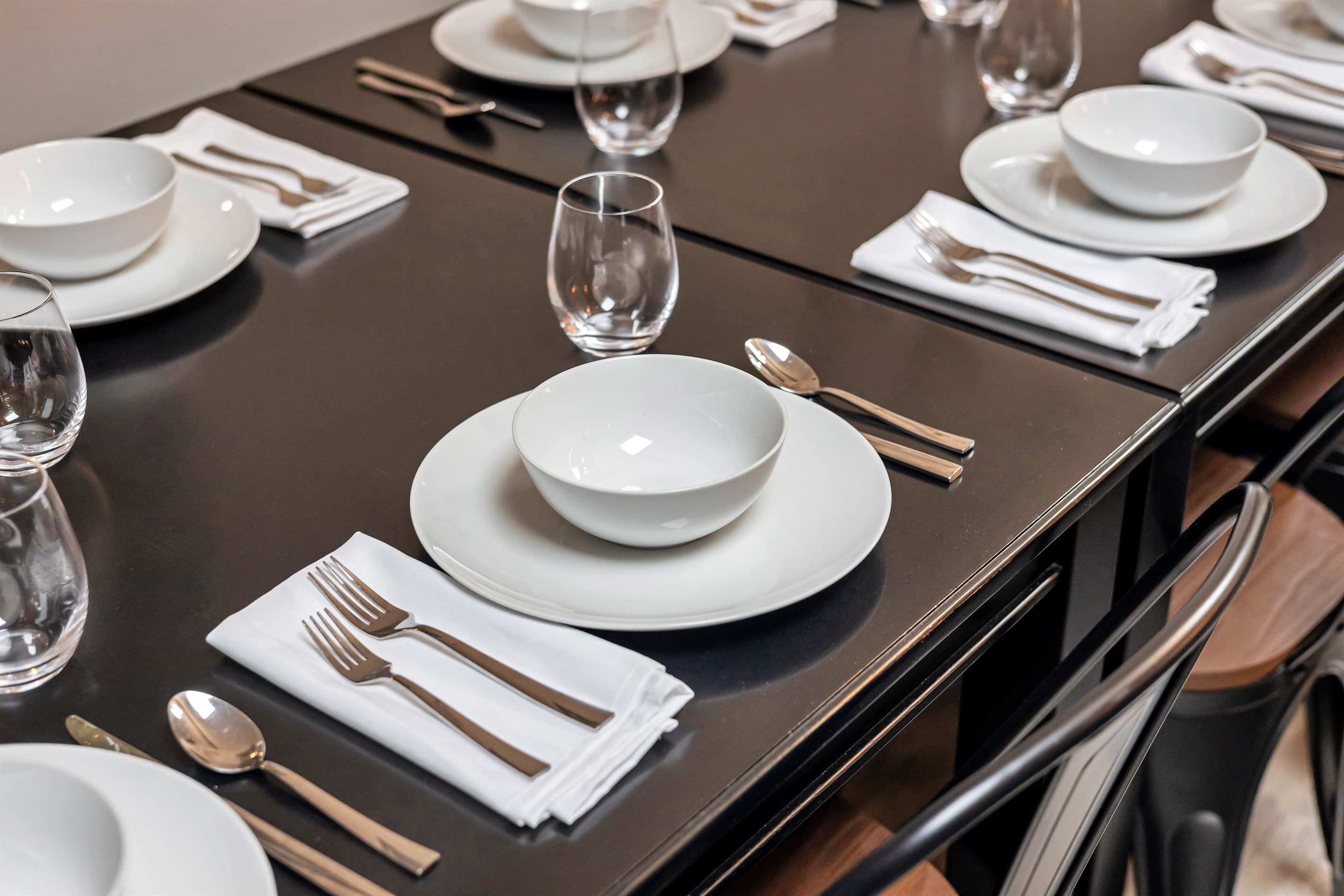 Admire the elegant dining setup of plates, bowls, and forks, perfect for your next meal. Staged photo