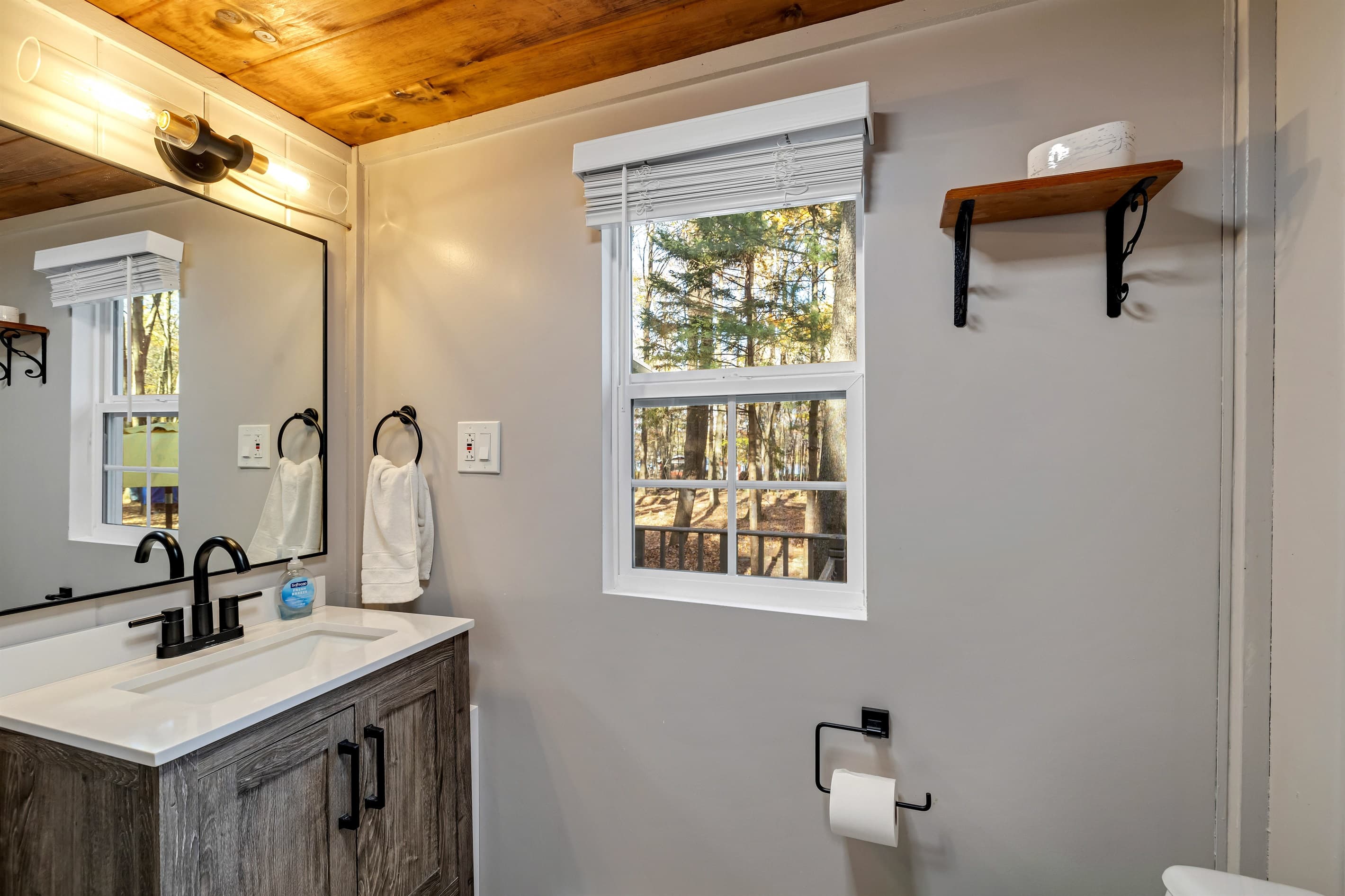 Bathroom with a toilet, sink, and corner shower, offering a practical space for your daily routine. Convenient and comfortable for your stay!
