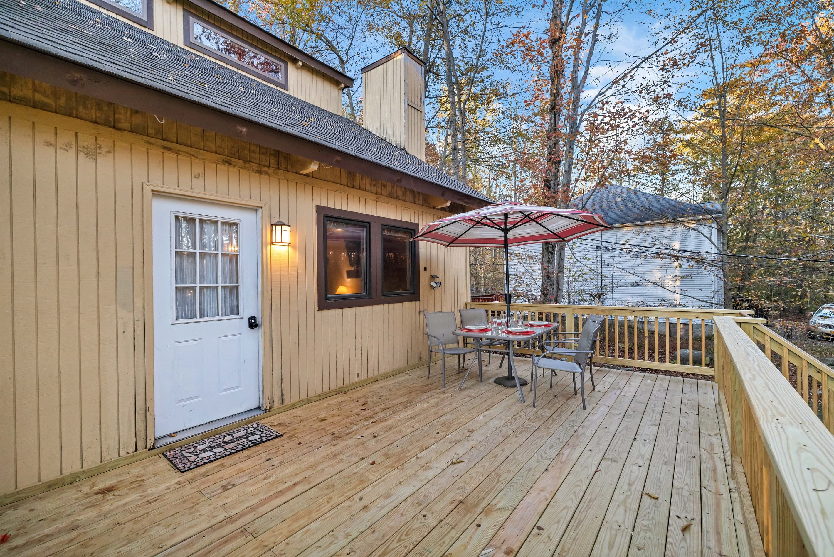 Welcoming front porch/deck featuring an outdoor table with an umbrella and seating, perfect for enjoying meals or relaxing in the fresh air