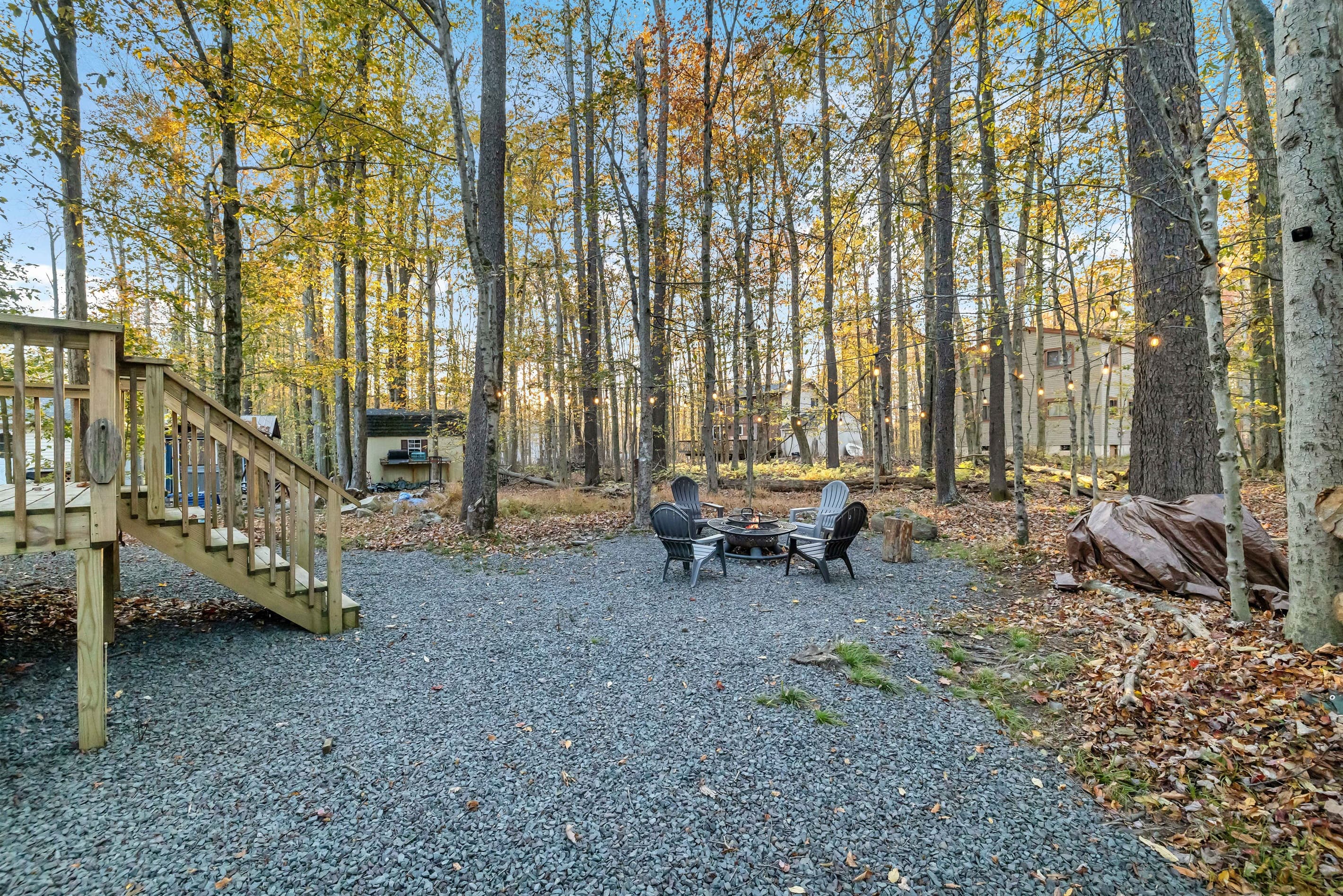 Charming backyard with string lights creating a warm ambiance, a firepit with seating for cozy evenings under the stars—perfect for gathering with friends and family