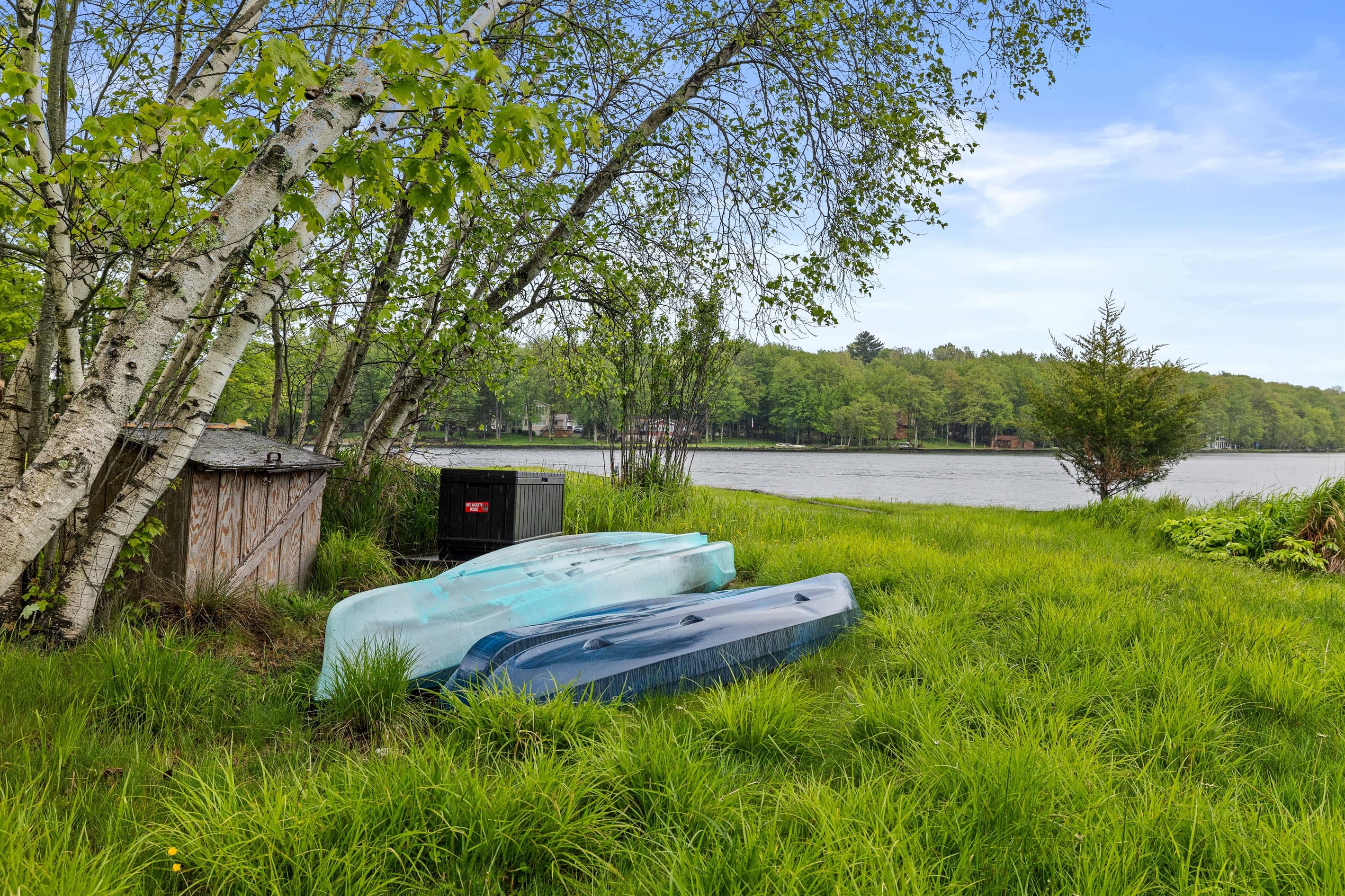 Lakefront backyard with a grassy lawn, spacious deck overlooking the water, and a private dock for relaxing or launching a kayak.