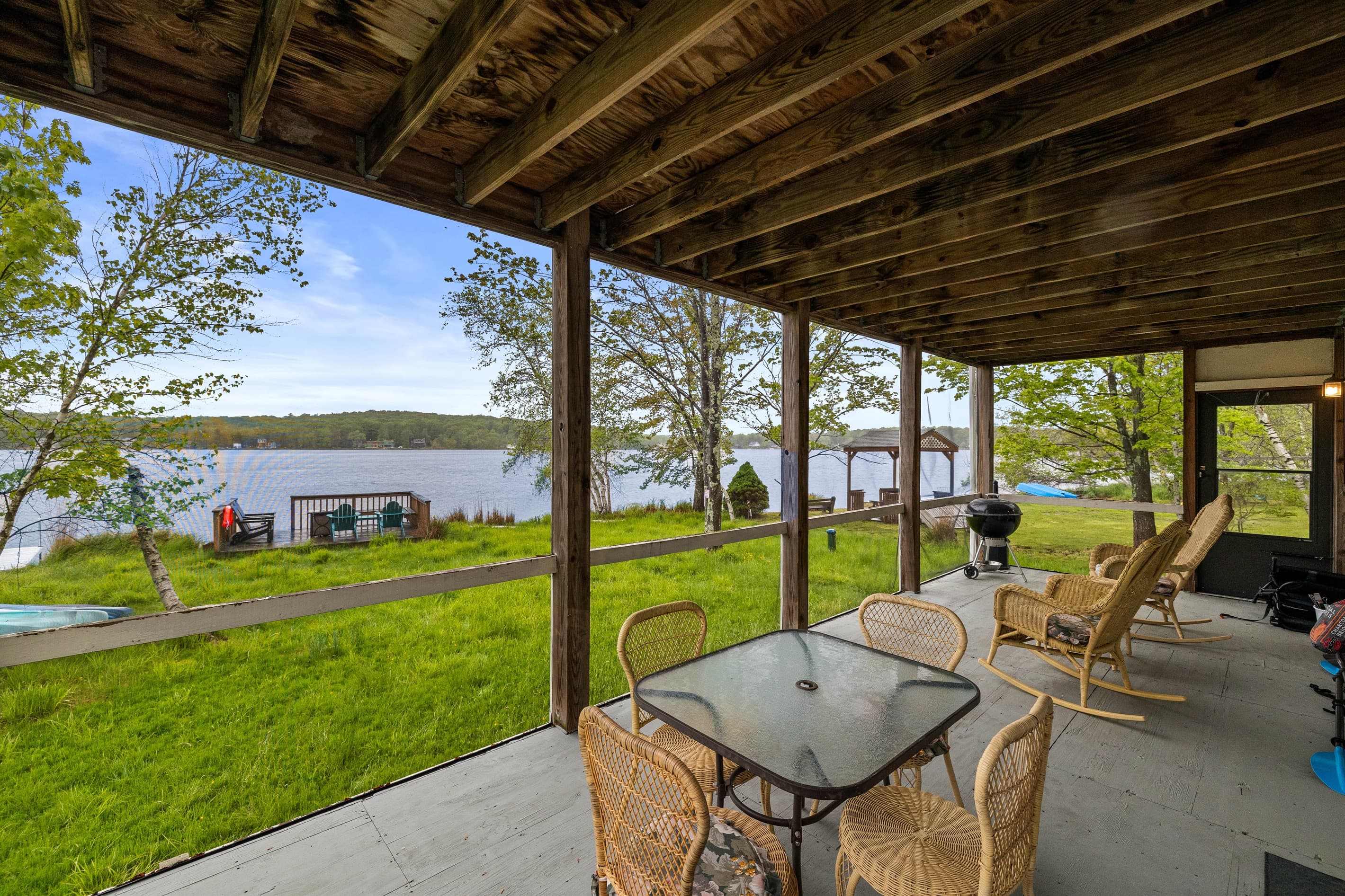 Covered patio with a BBQ grill, seating, and a small outdoor table—perfect for enjoying lake views.