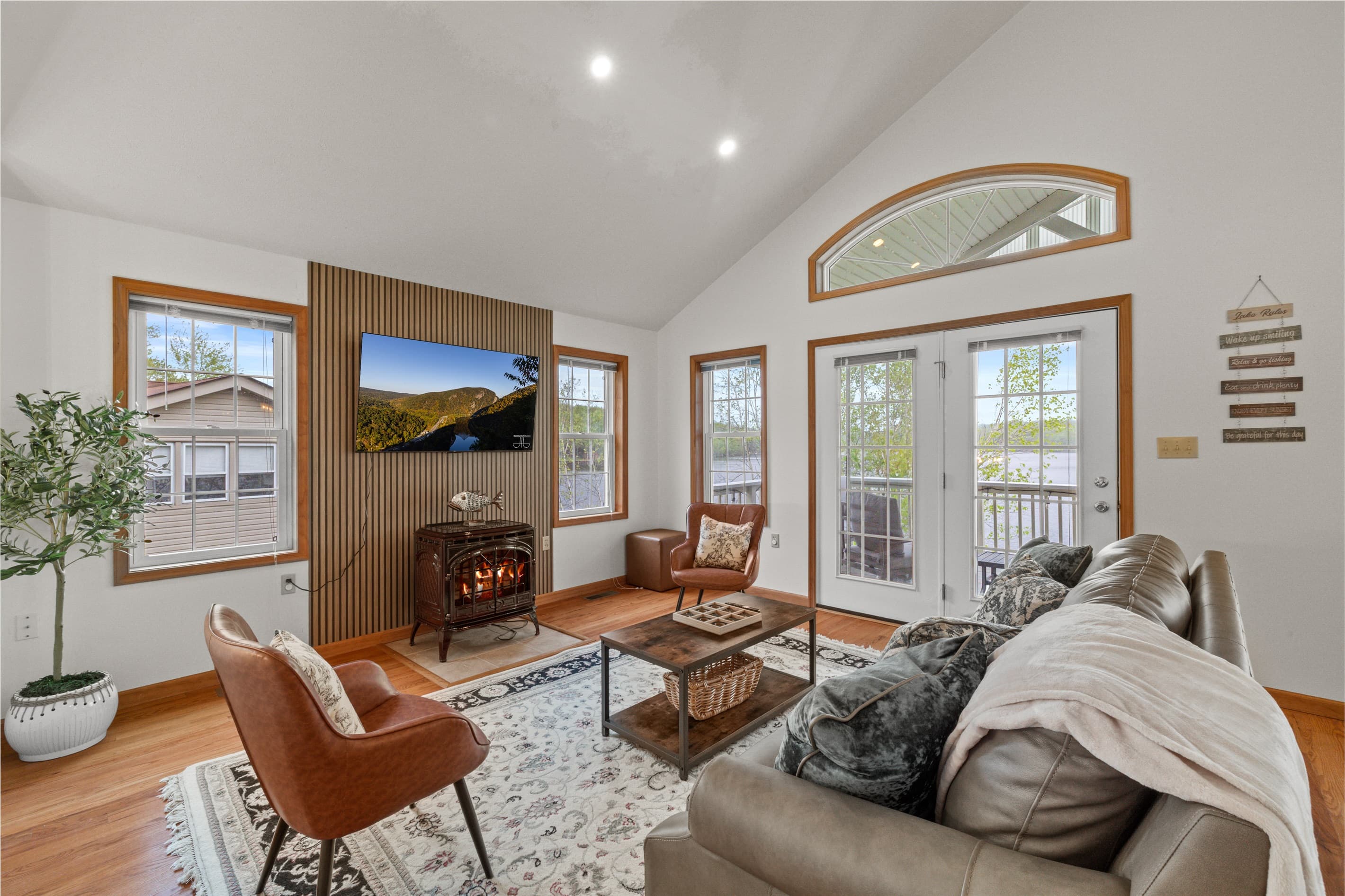 Living room with Smart TV to stream favorite shows, comfortable sofa and chairs. Exit to balcony with lakeview
