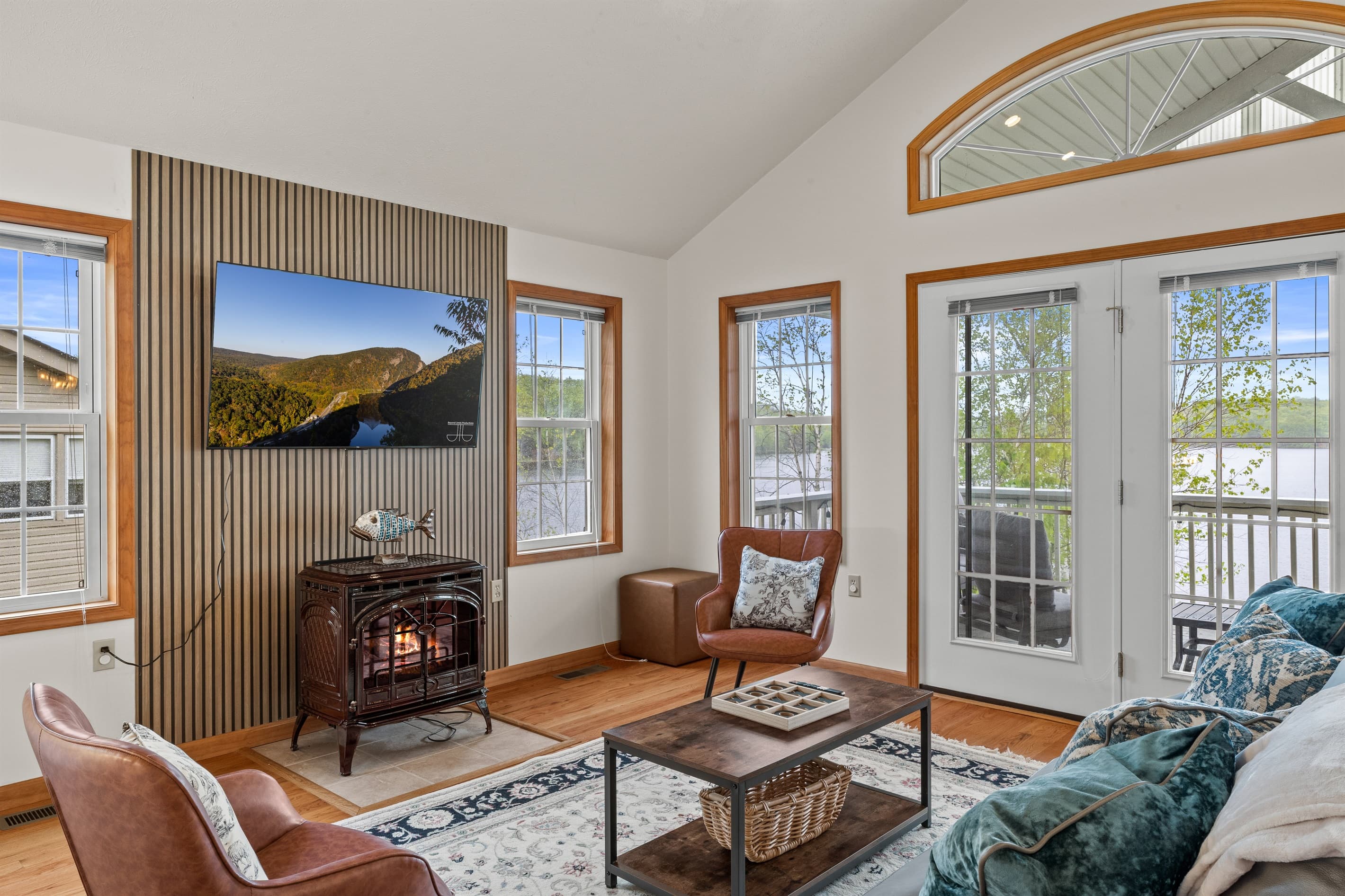 Living room with Smart TV to stream favorite shows, comfortable sofa and chairs. Exit to balcony with lakeview