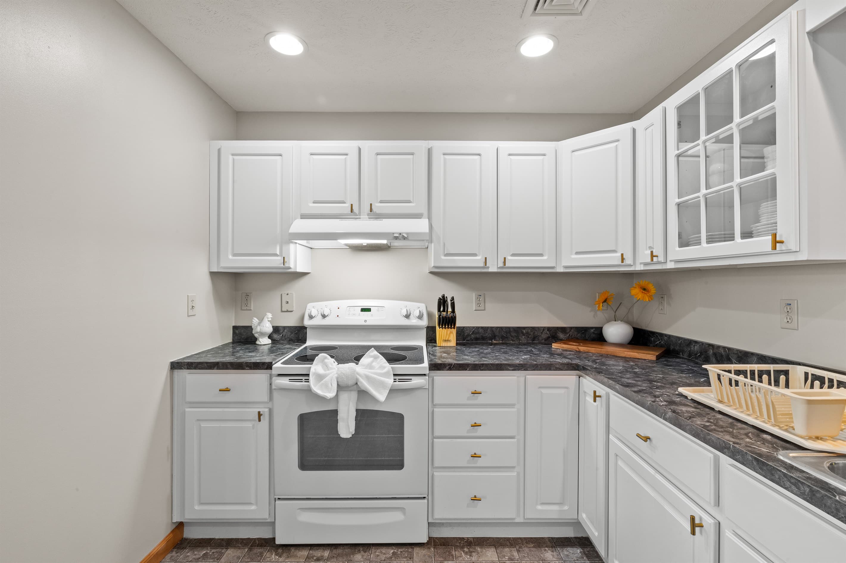 Fully stocked kitchen with white appliances, stainless sink, dishwasher, microwave, toaster, and coffee maker.